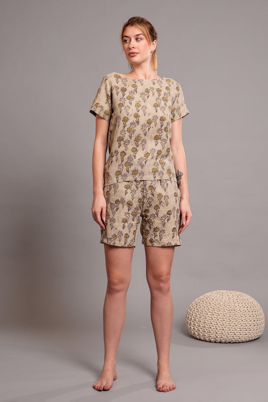 Woman wearing a matching linen floral top and shorts set against a beige background.