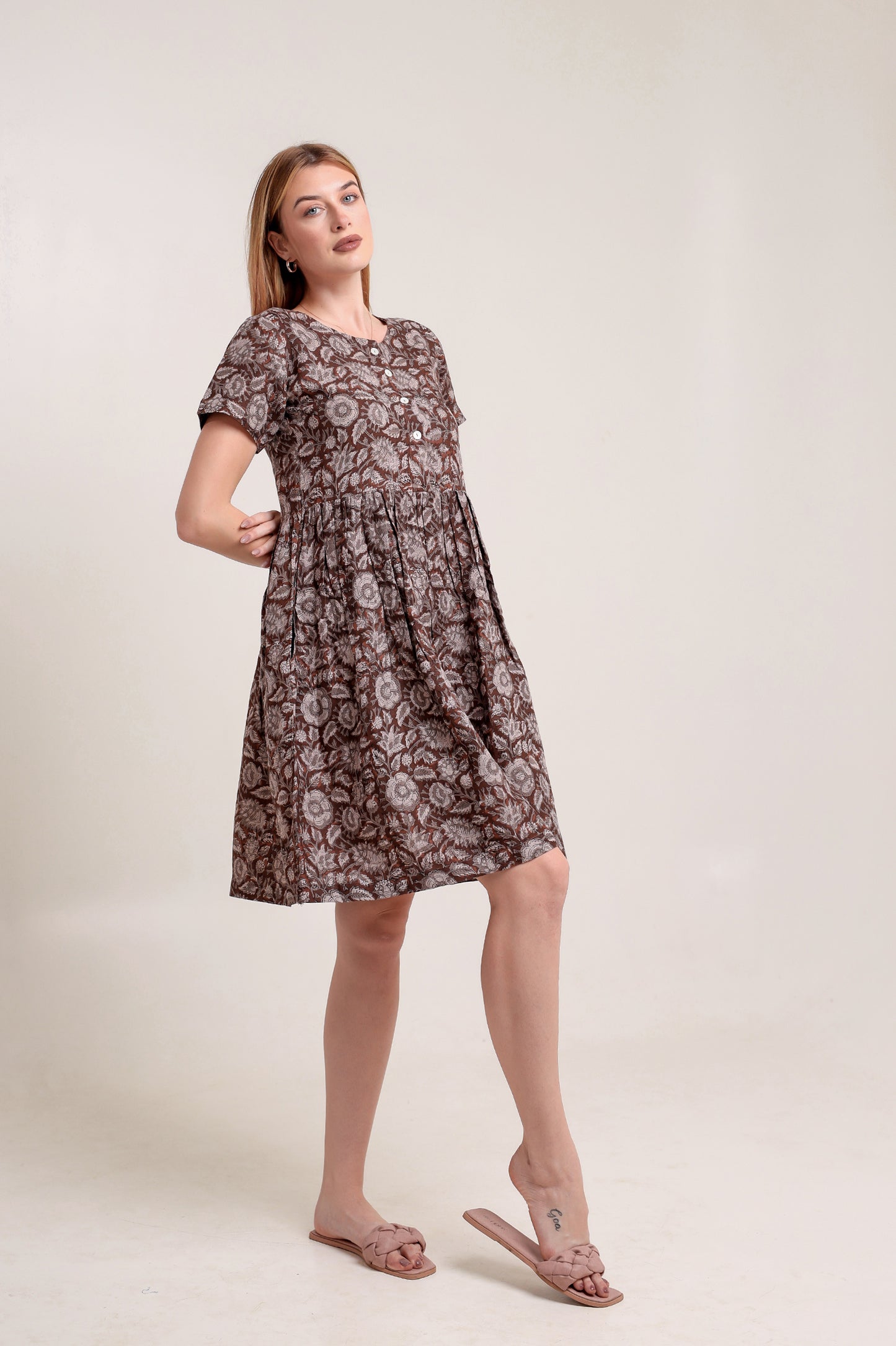 Woman wearing a brown floral linen mini dress against a plain background.