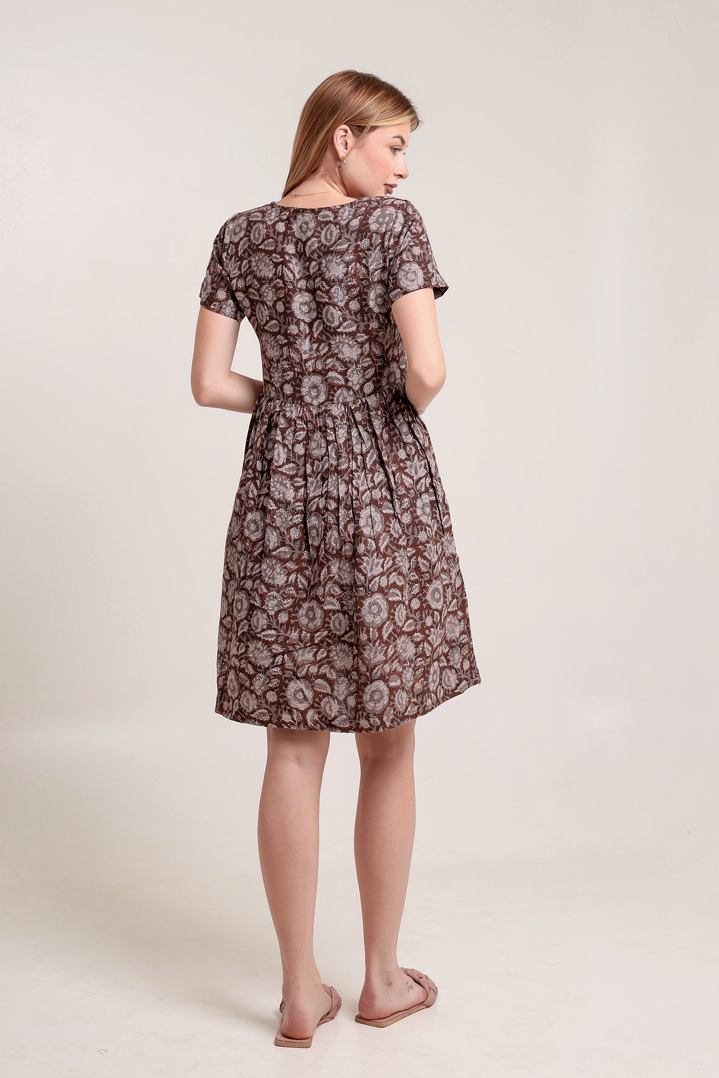 Woman wearing a patterned linen mini dress against a plain background.