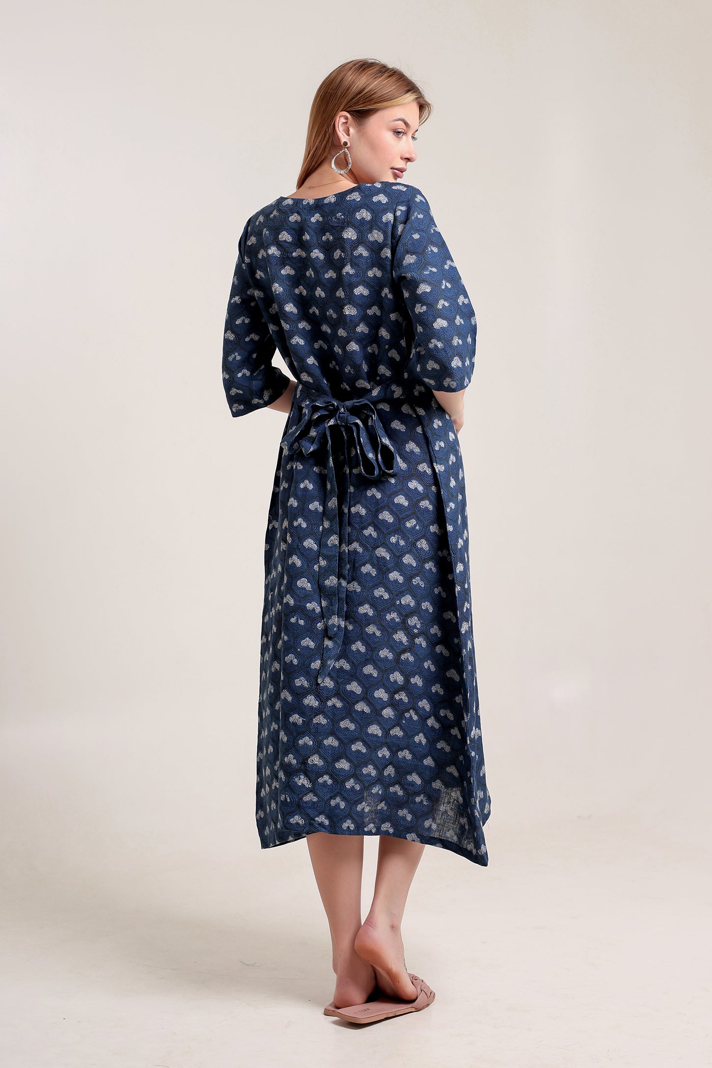 Woman wearing a blue patterned linen floral maxi dress against a white background.