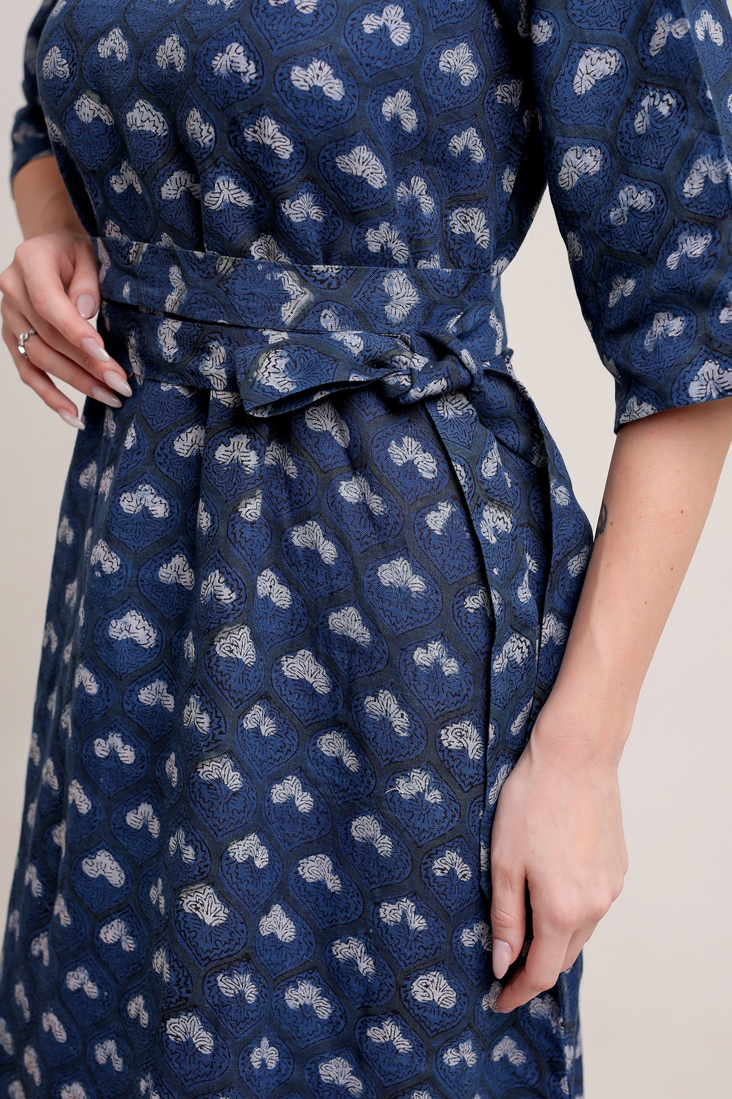 Person wearing a navy blue linen floral maxi dress with white patterns against a neutral background.