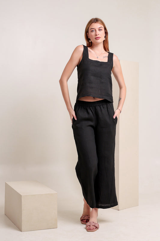 Woman wearing a black linen sleeveless top and pants set against a plain background.