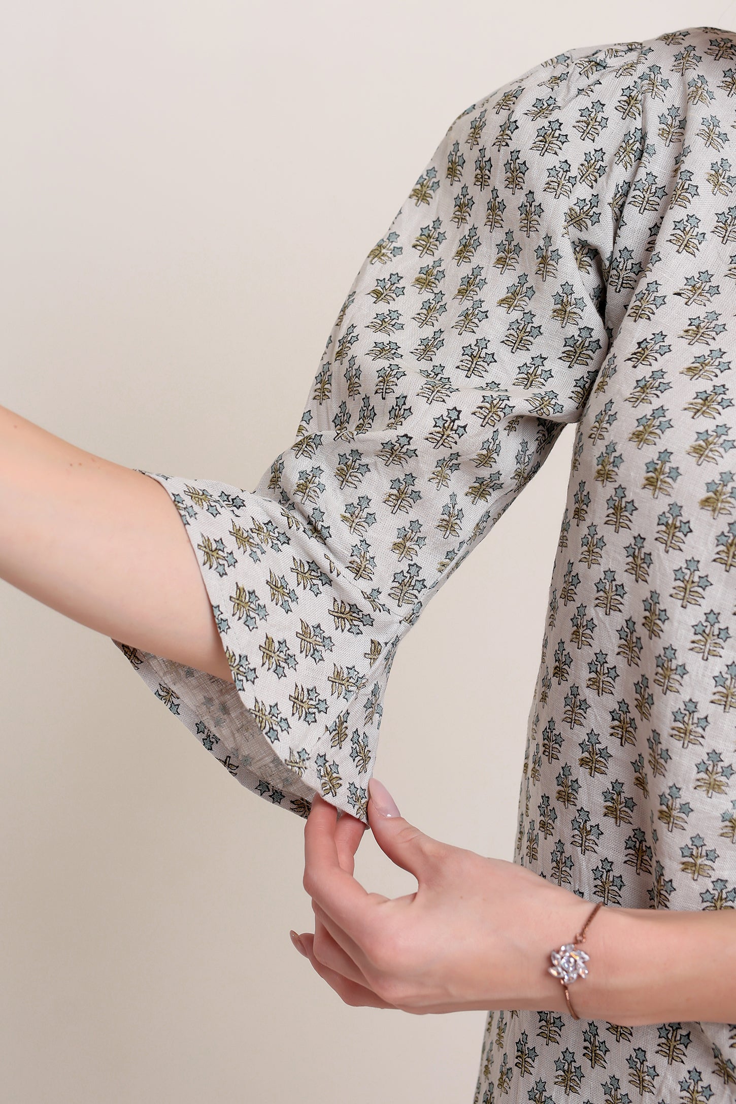Close-up of a person wearing a floral-patterned linen mini dress against a neutral background.
