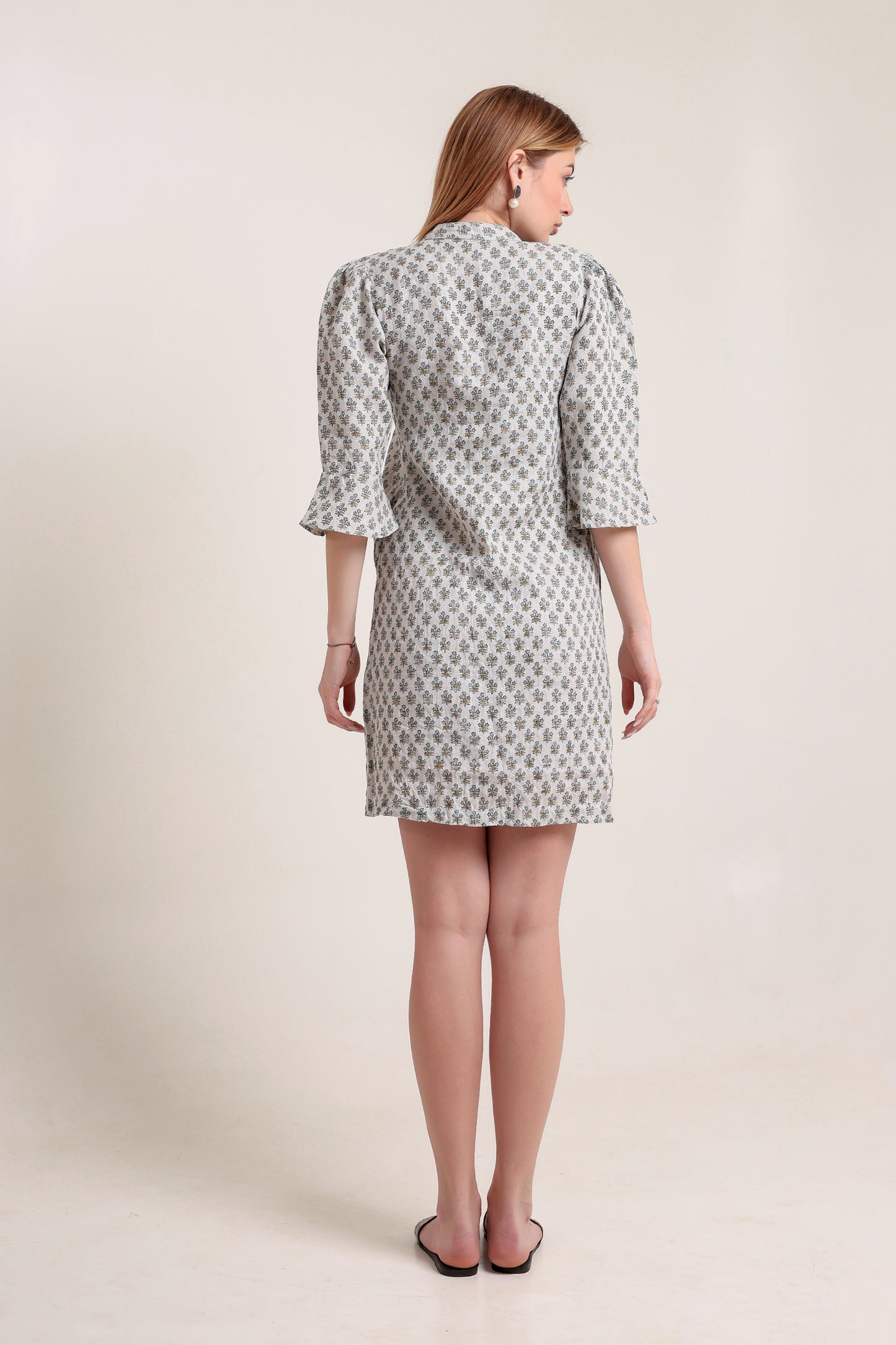 Woman wearing a patterned linen mini dress against a plain background.