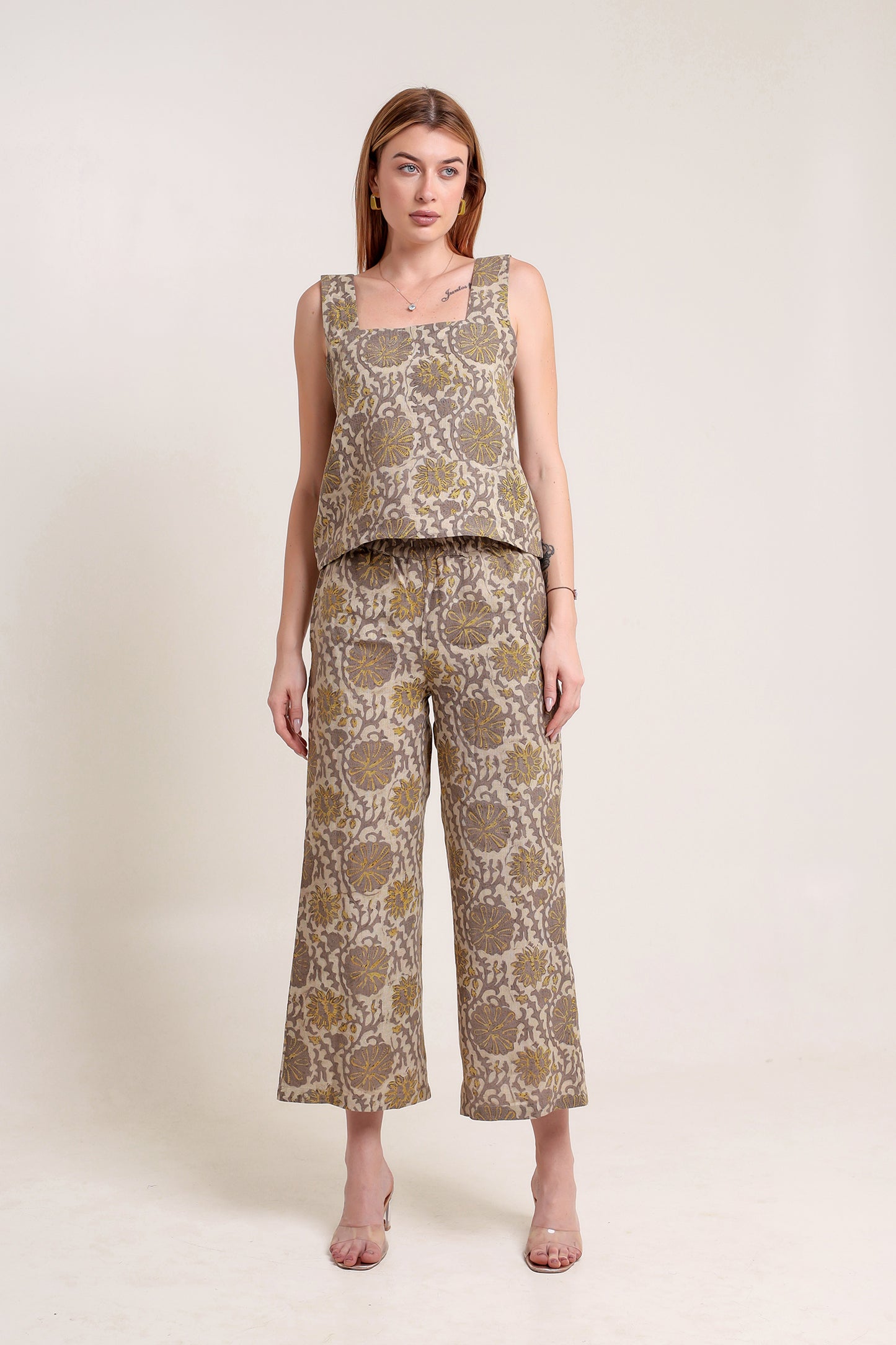 Woman wearing a patterned linen top and pants set against a plain background.