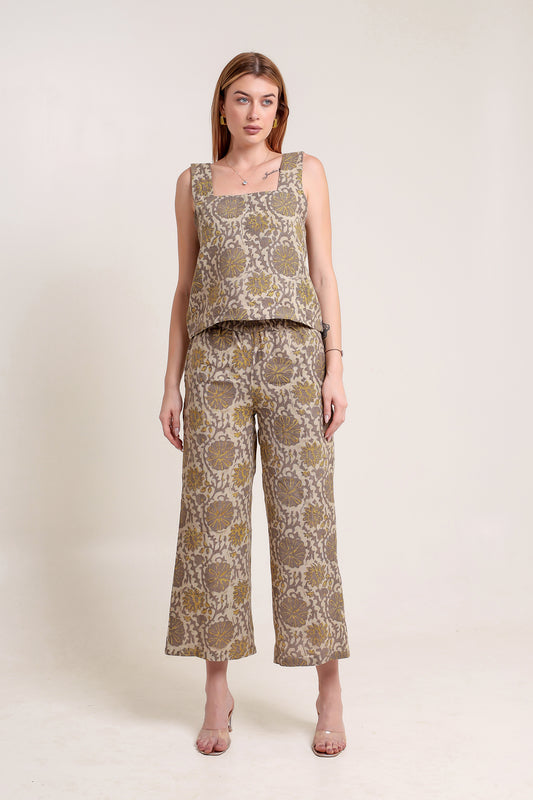 Woman wearing a patterned linen top and pants set against a plain background.