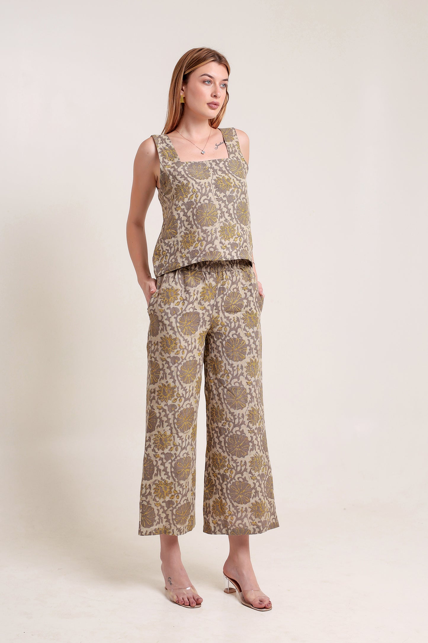 Woman wearing a patterned linen top and pants set against a plain background.
