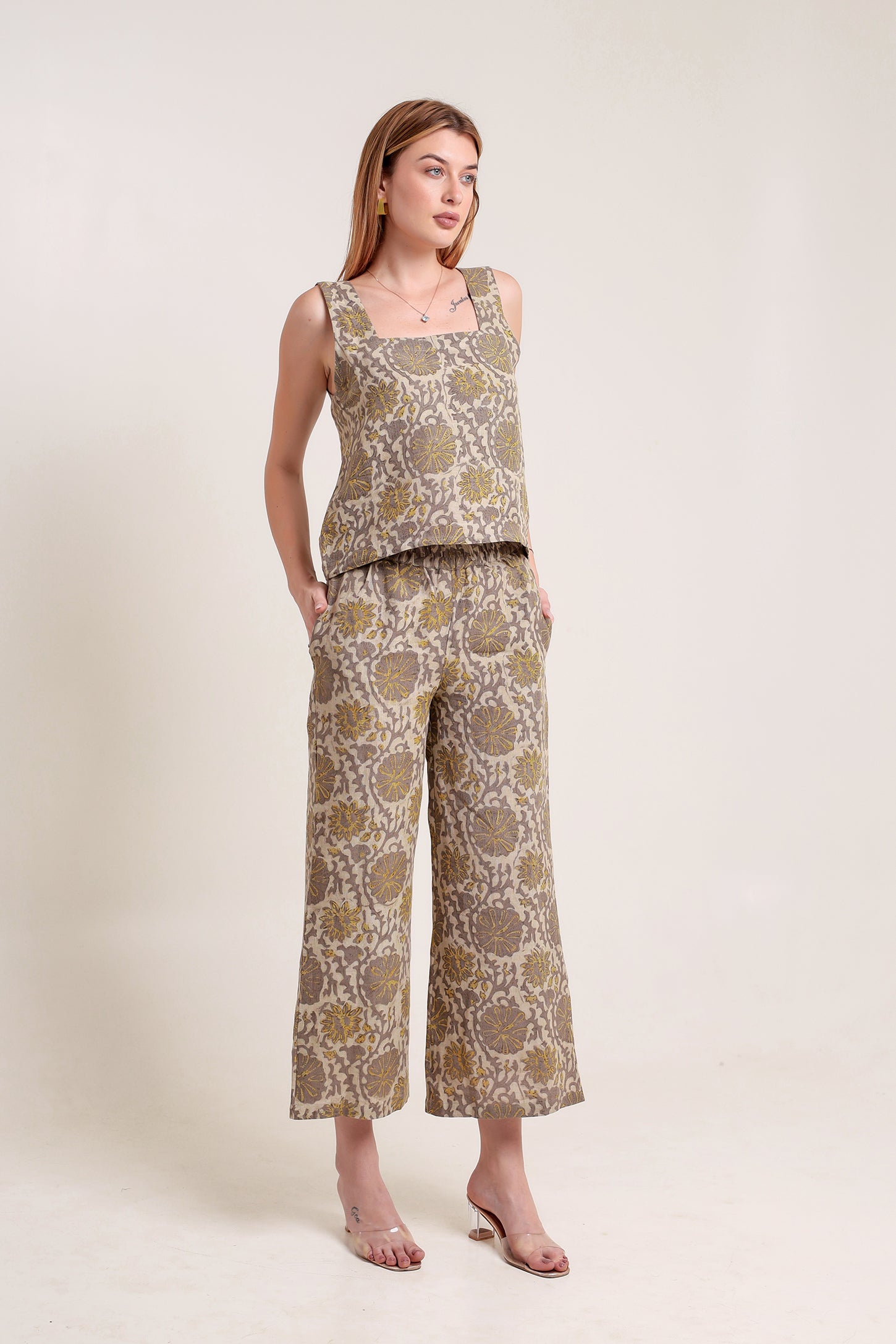 Woman wearing a patterned linen top and pants set against a plain background.