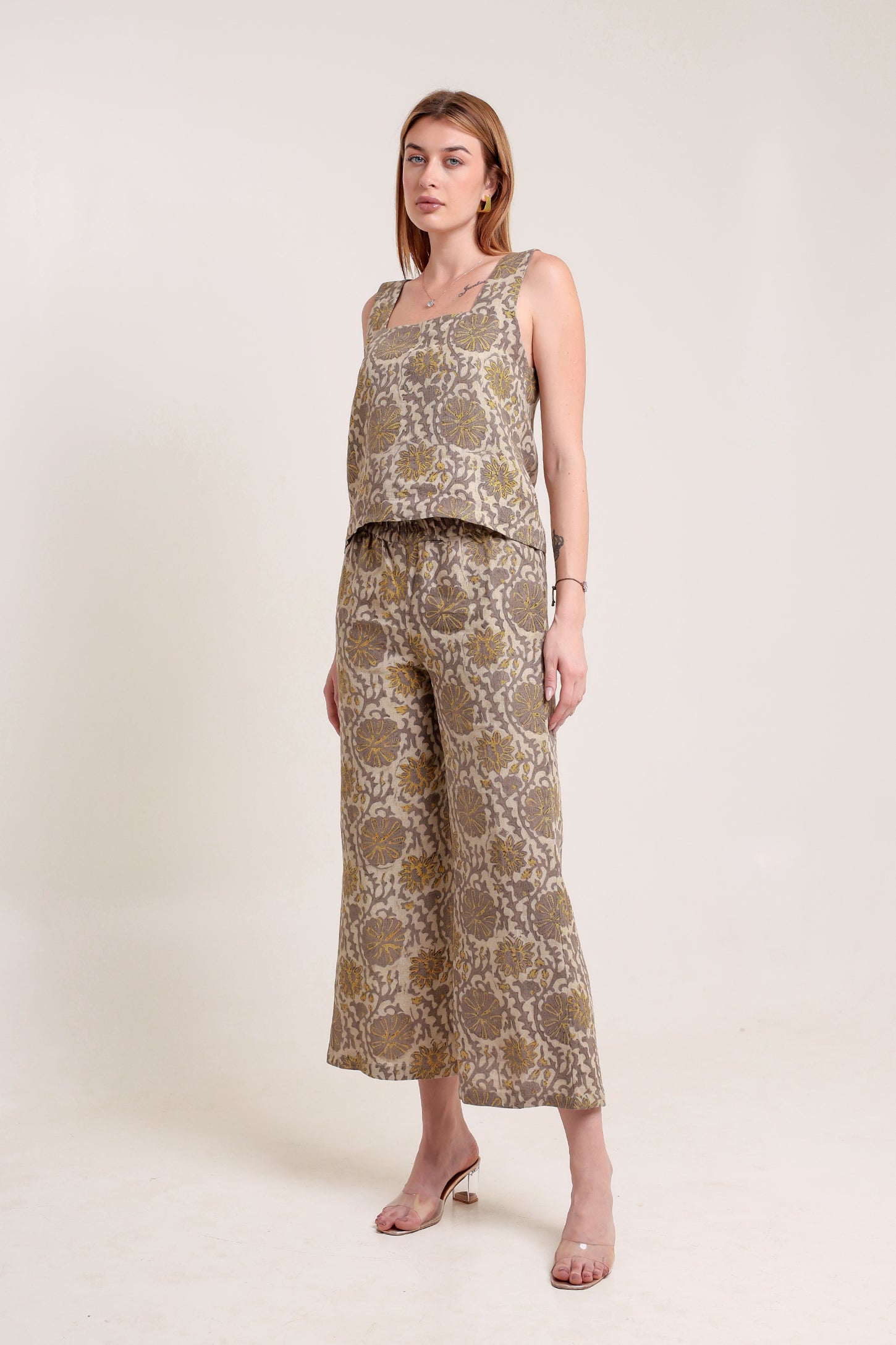 Woman wearing a patterned linen top and pants set against a white background.