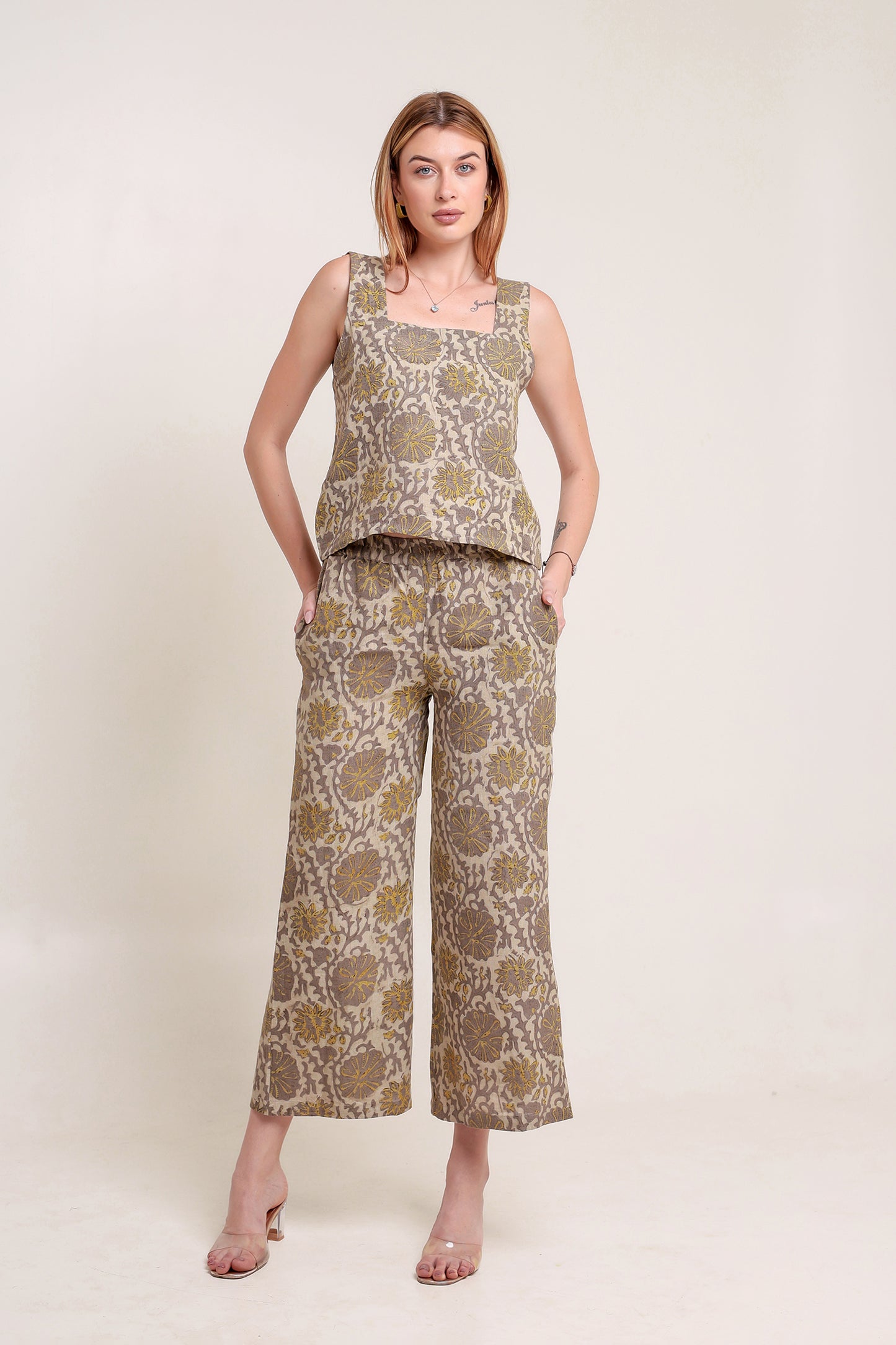 Woman wearing a patterned linen top and pants set against a plain background.