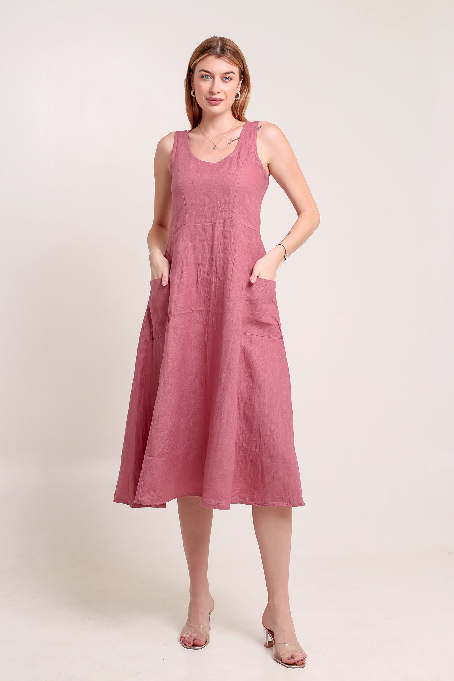 Woman wearing a pink sleeveless linen midi dress against a plain background.
