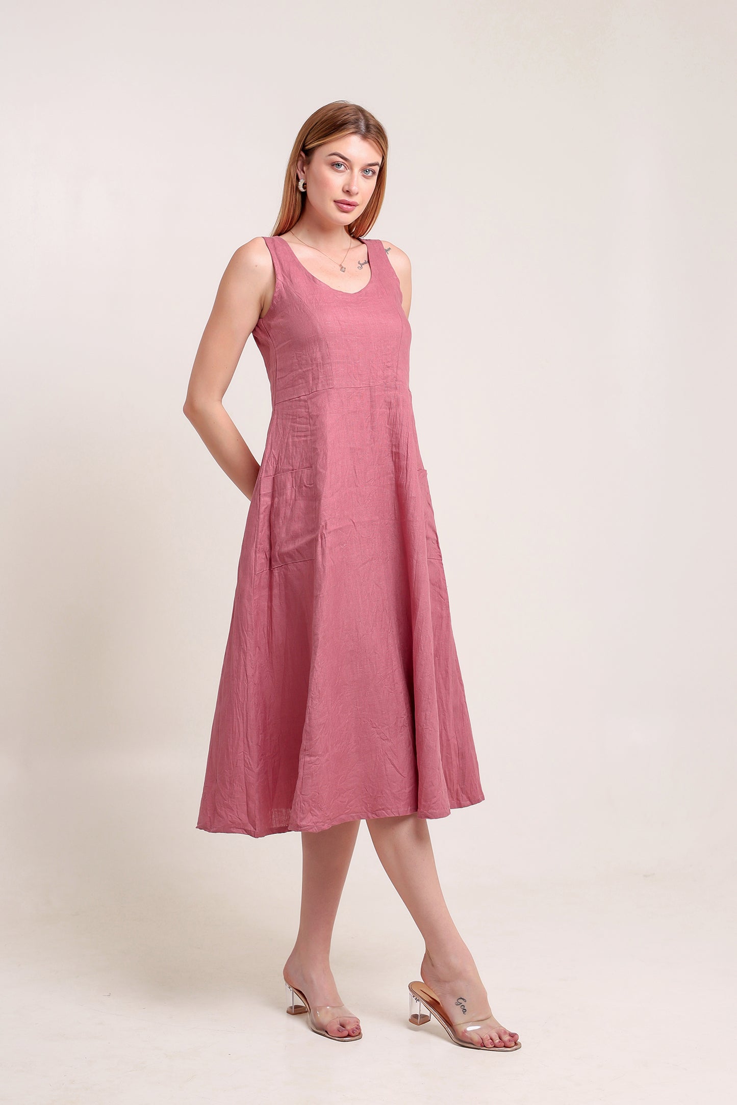 Woman wearing a pink sleeveless linen midi dress against a plain background.