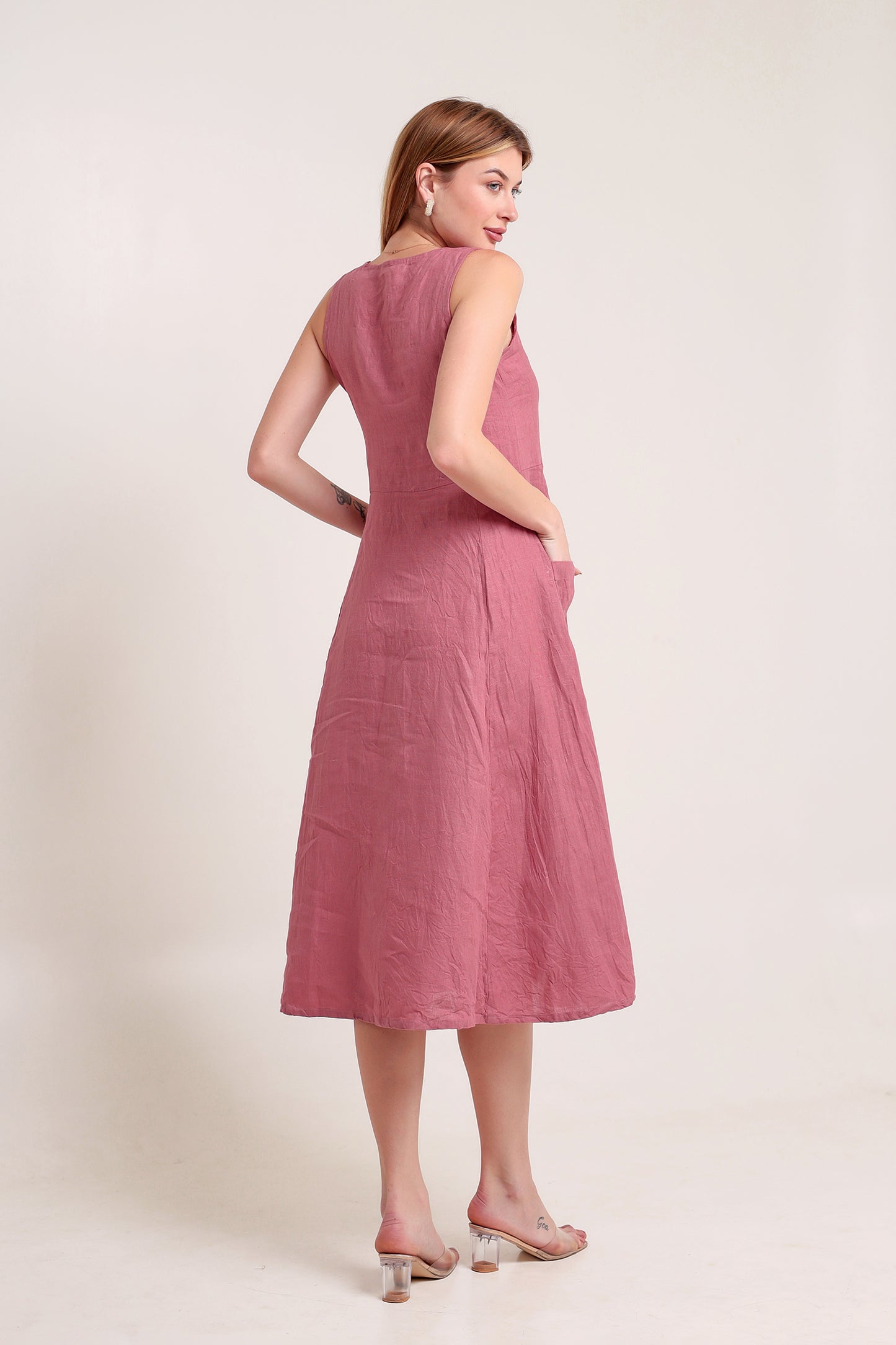 Woman wearing a pink linen midi dress against a plain background.