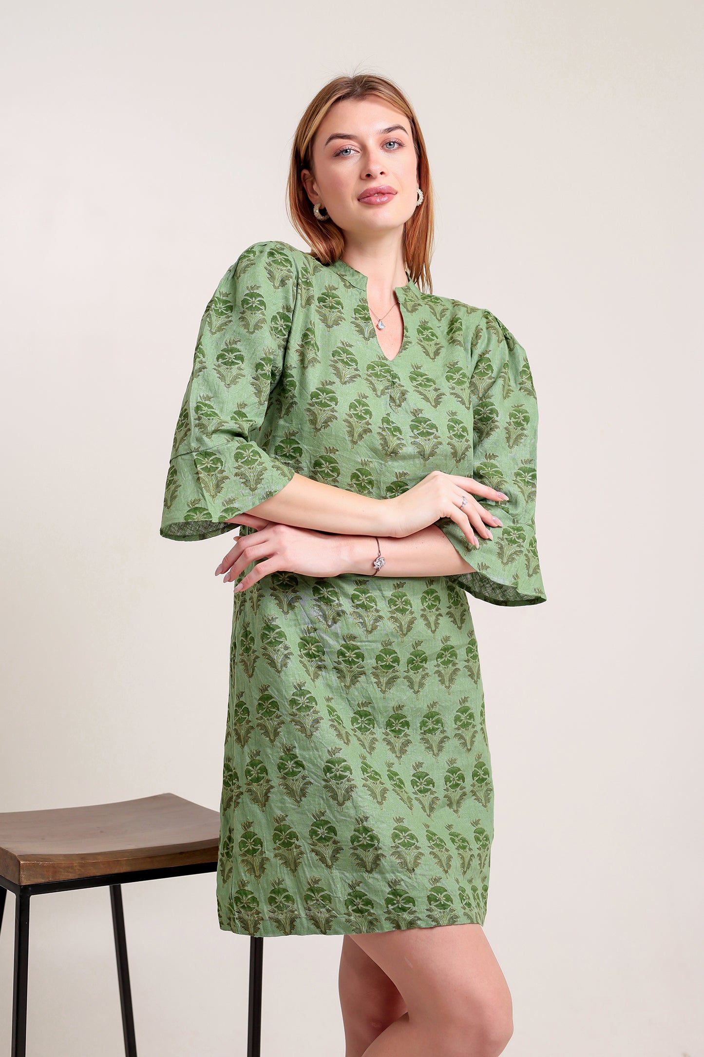 Woman wearing a green patterned linen mini dress against a plain background.