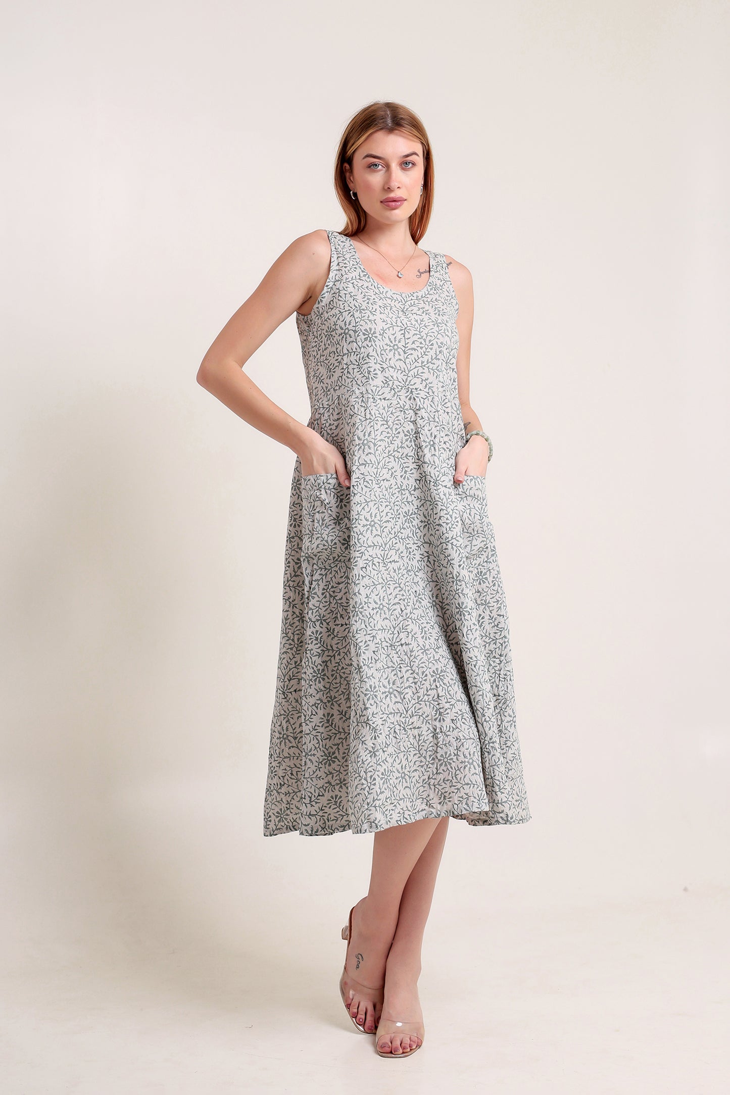 Woman wearing a gray floral linen floral maxi dress against a plain background.