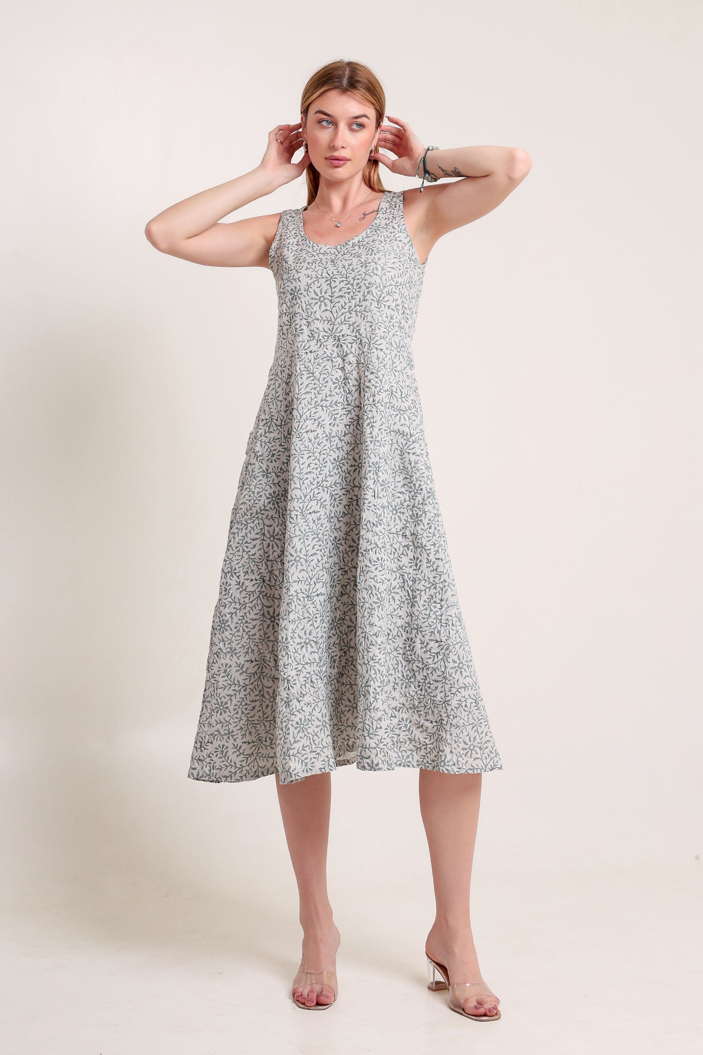Woman wearing a gray floral linen floral maxi dress against a plain background.