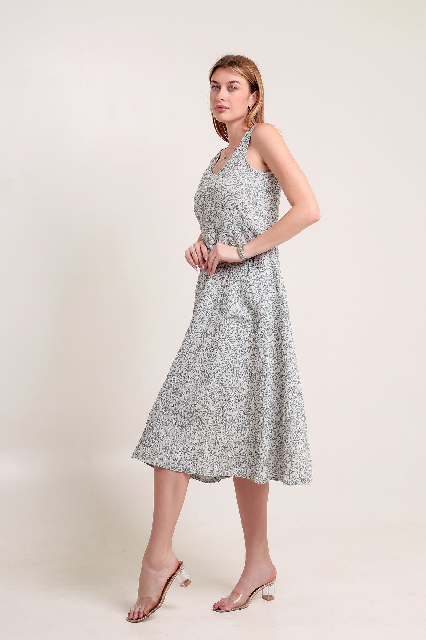 Woman wearing a silver floral linen floral maxi dress against a white background.