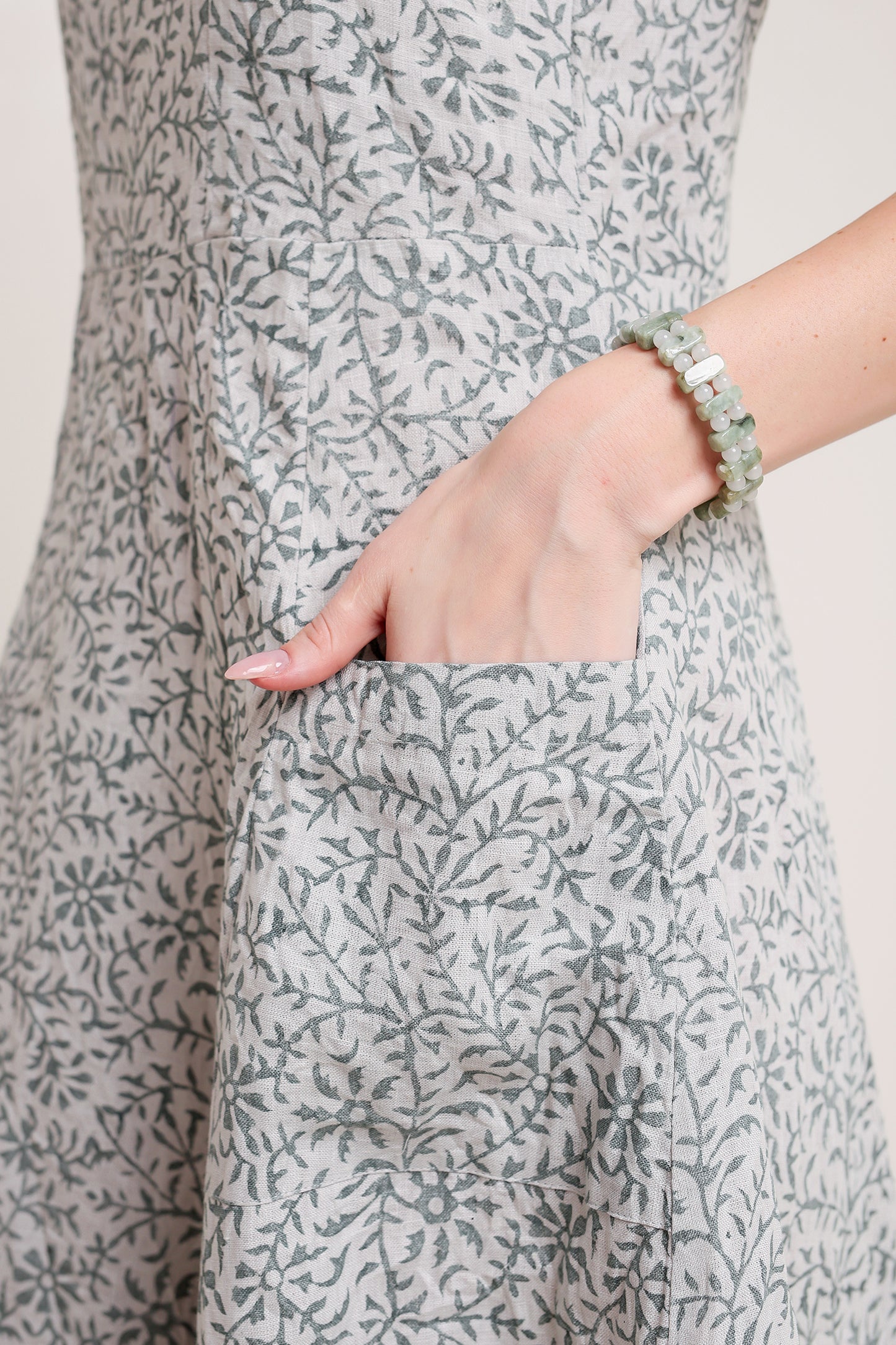 Person wearing a gray floral linen floral maxi dress with a close-up of the pocket.