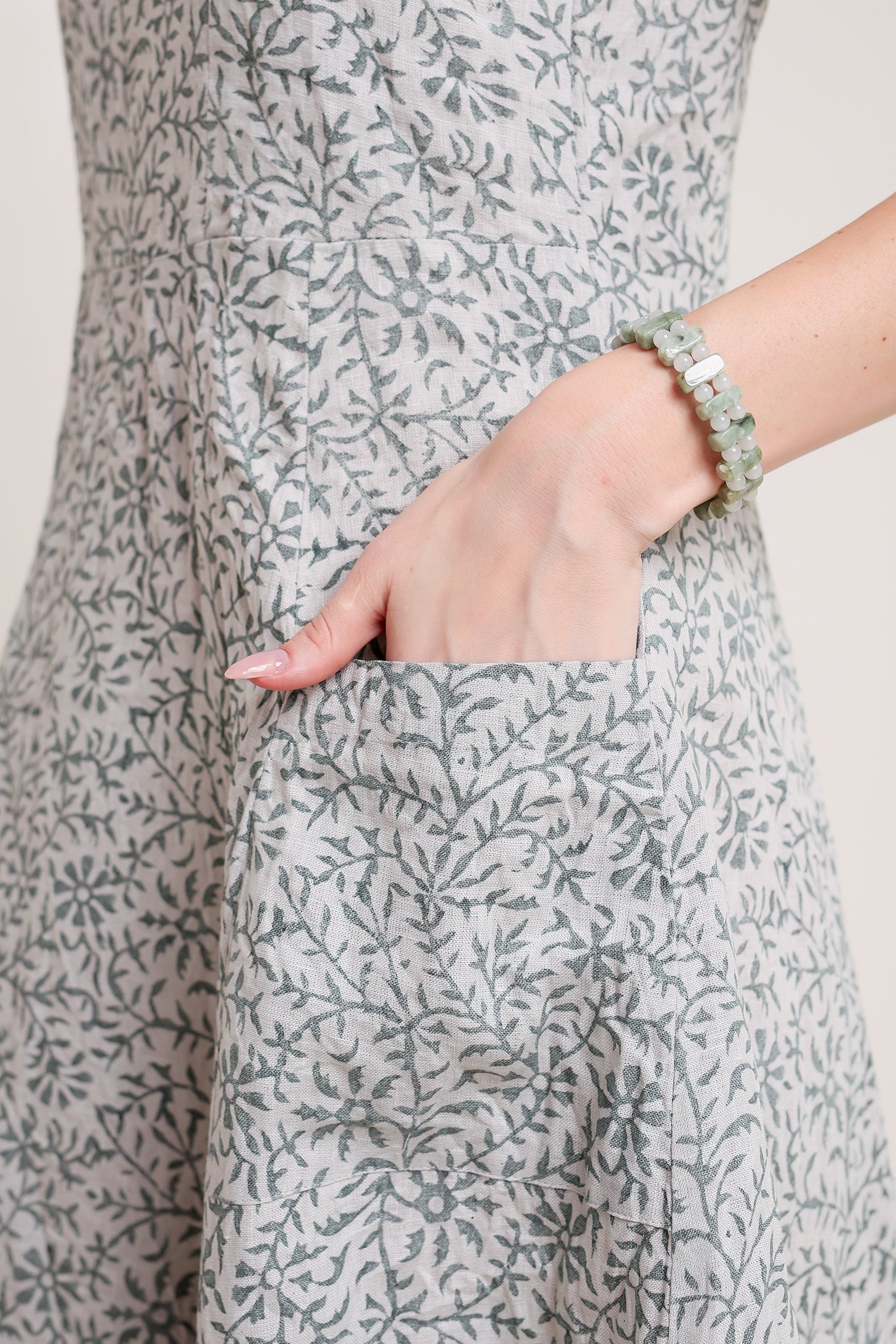 Person wearing a gray floral linen floral maxi dress with a close-up of the pocket.