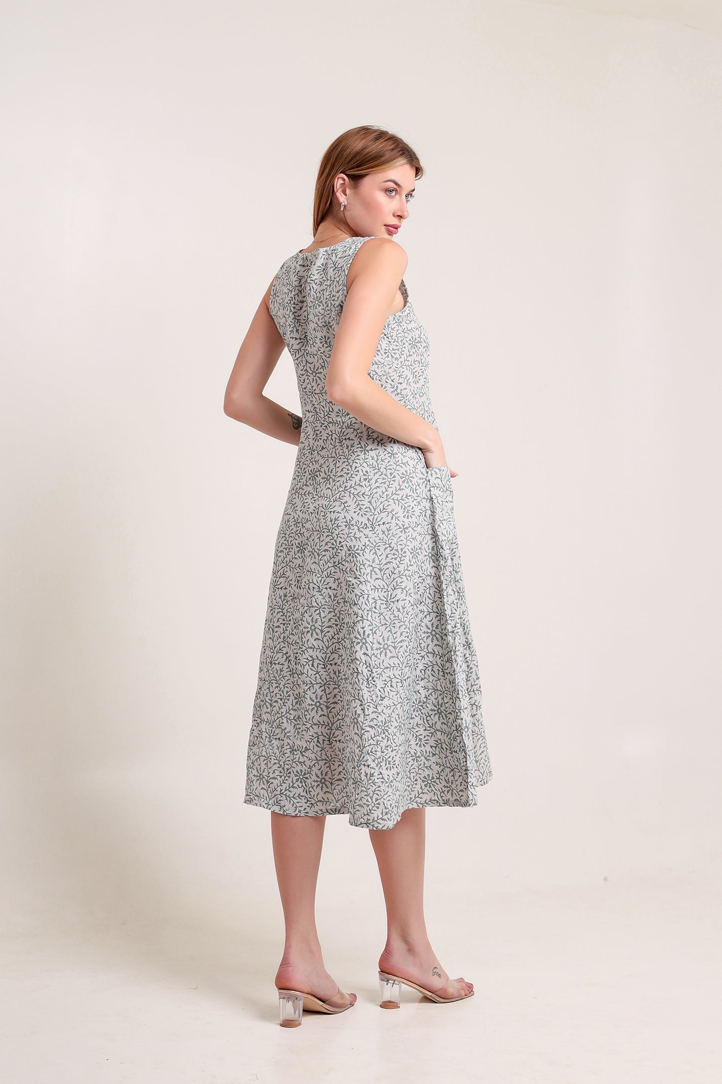 Woman wearing a sleeveless patterned linen floral maxi dress against a plain background.