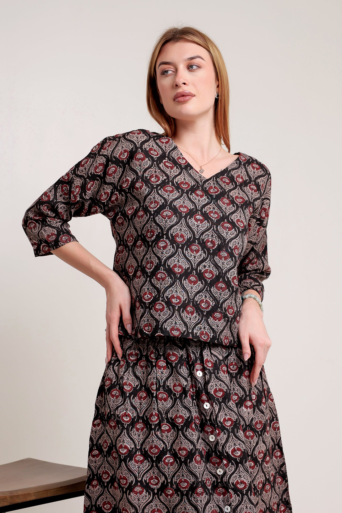 Woman wearing a stylish linen skirt and top set with patterns against a plain background.