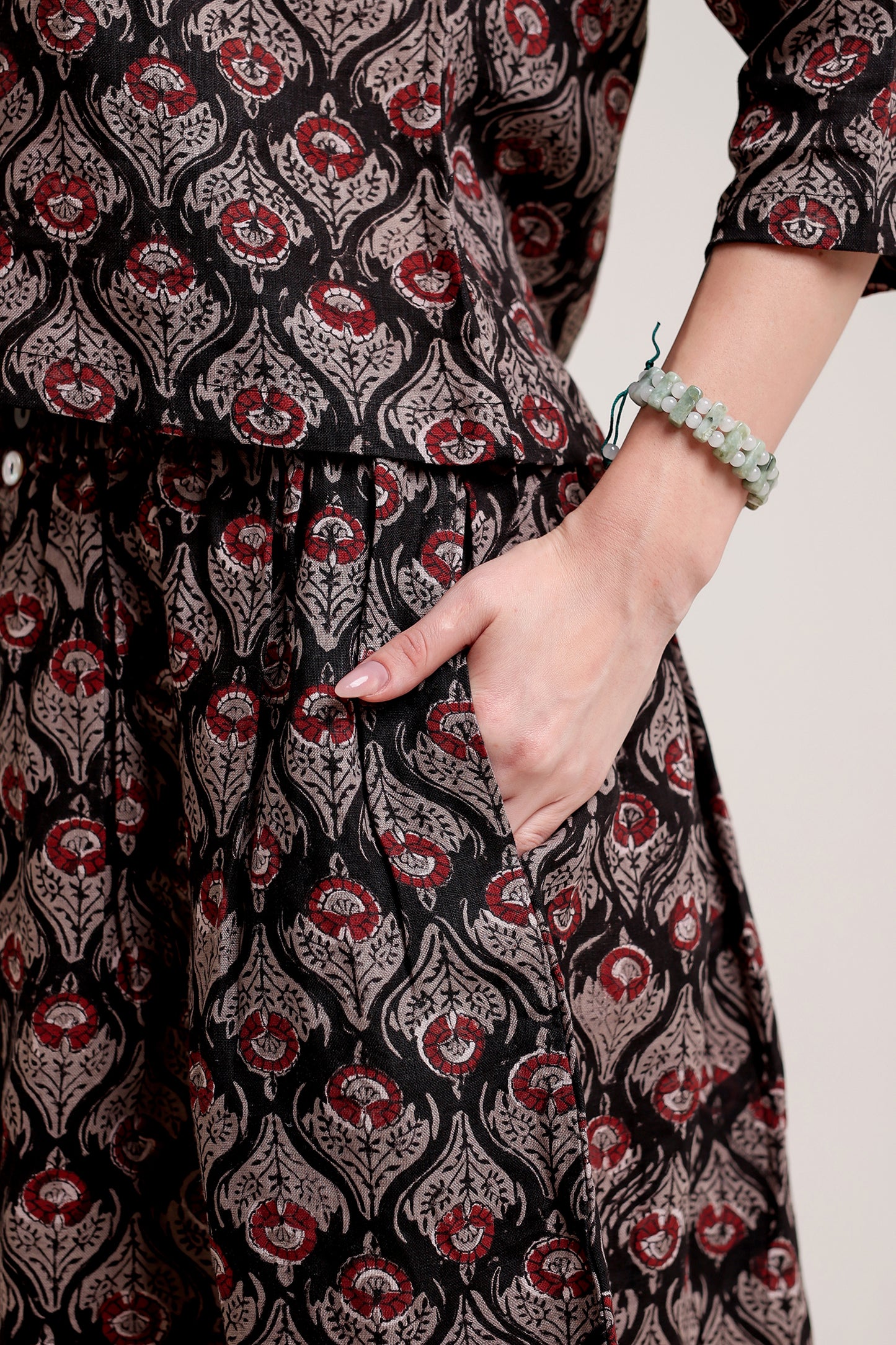 Person wearing a coordinated linen skirt and top set in black patterns against a beige background.