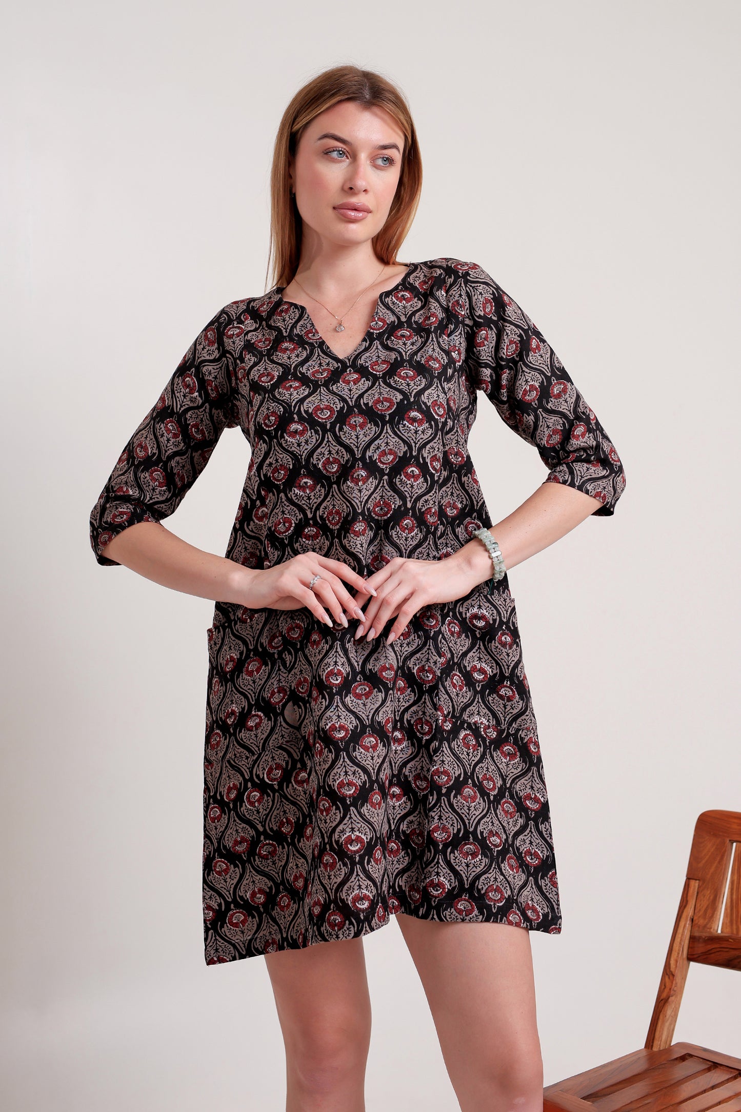 Woman wearing a patterned linen mini dress against a plain background.