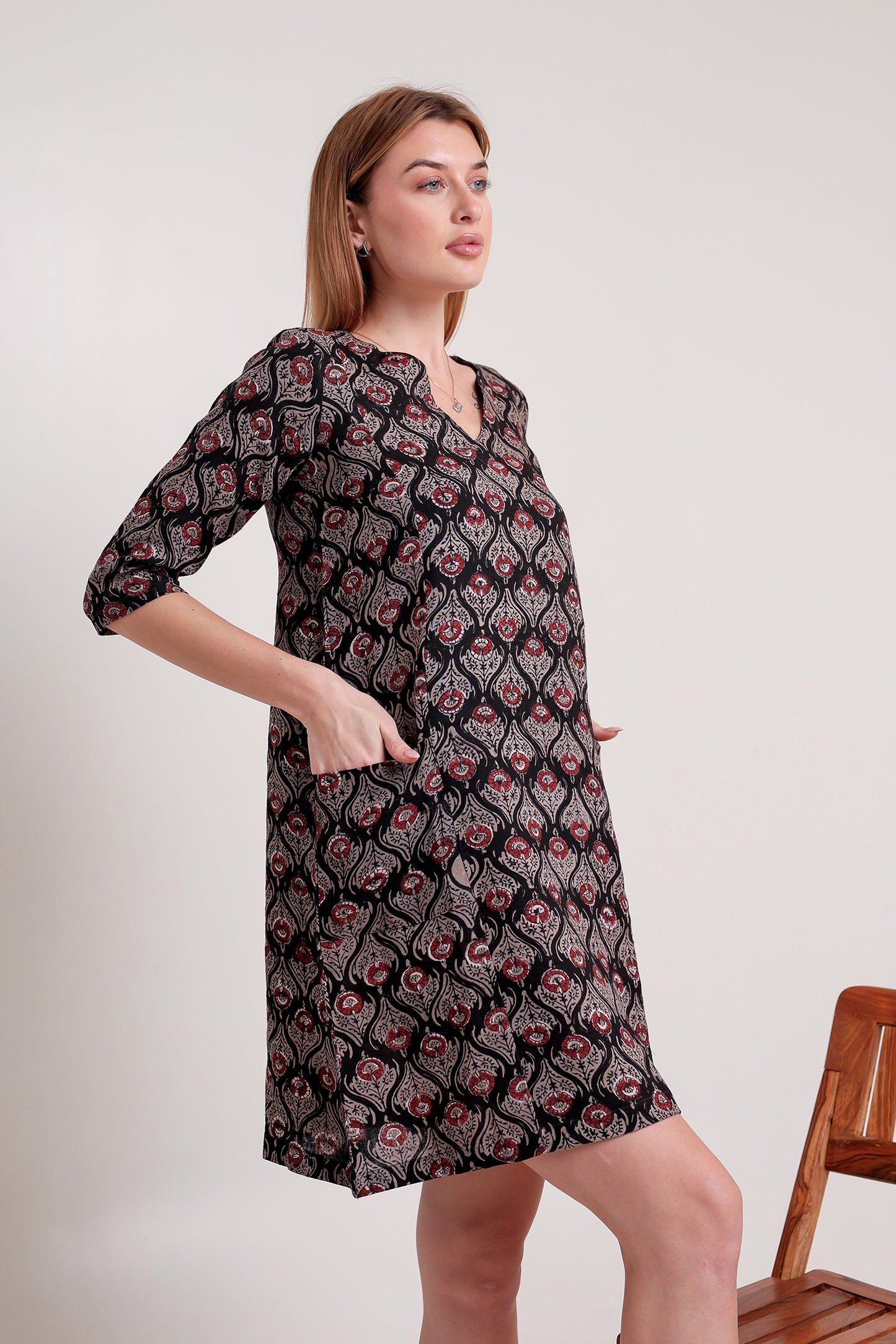 Woman wearing a black patterned linen mini dress against a white background.