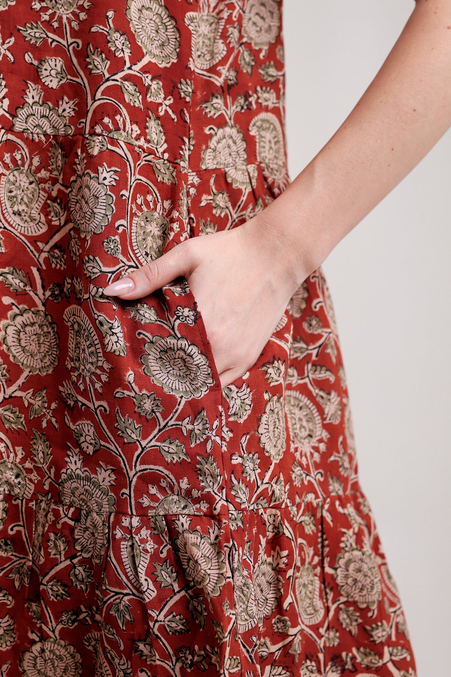 Red floral patterned linen floral mini dress with a hand in the pocket against a white background.