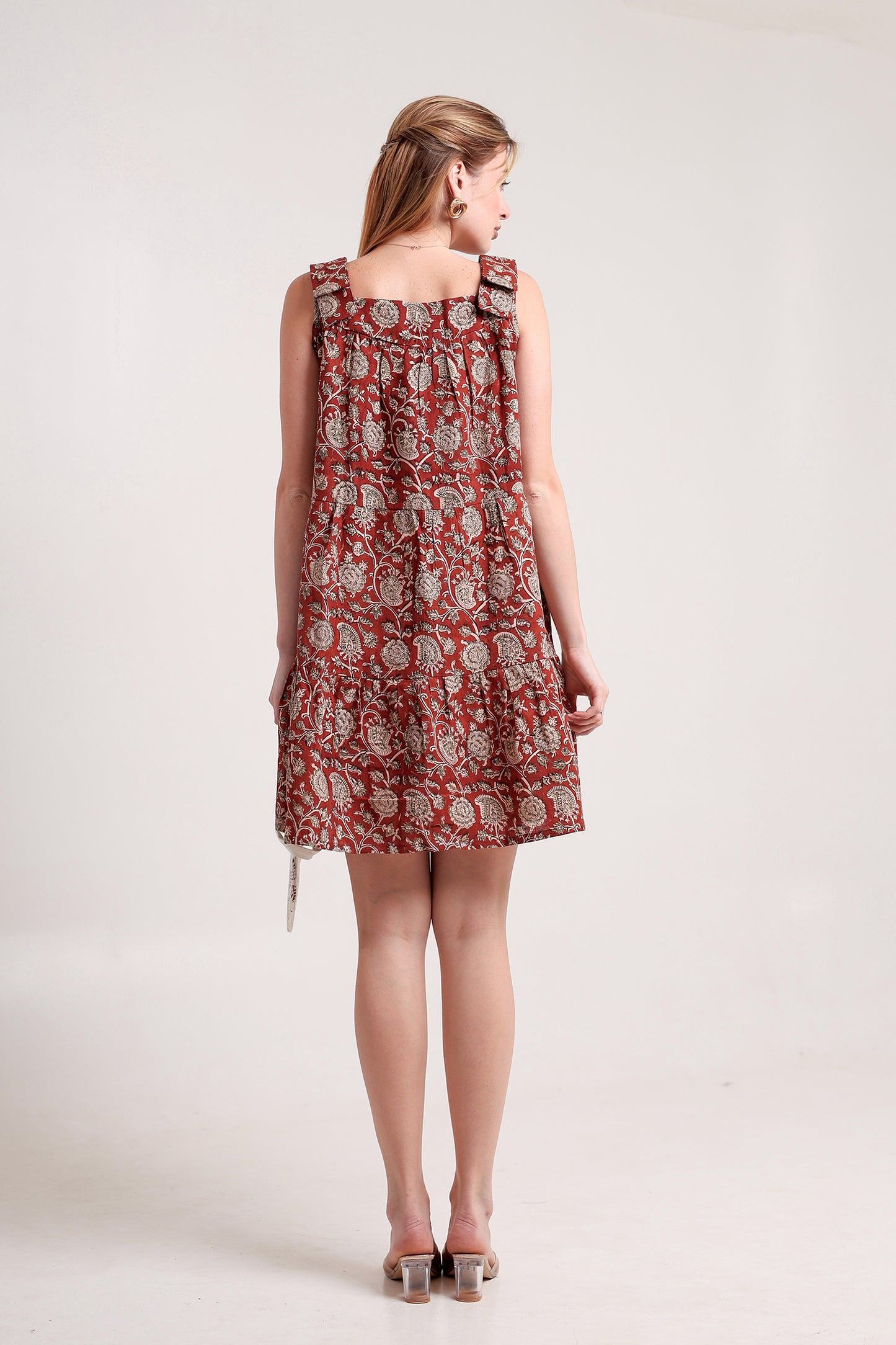 Woman wearing a red floral linen floral mini dress against a white background.