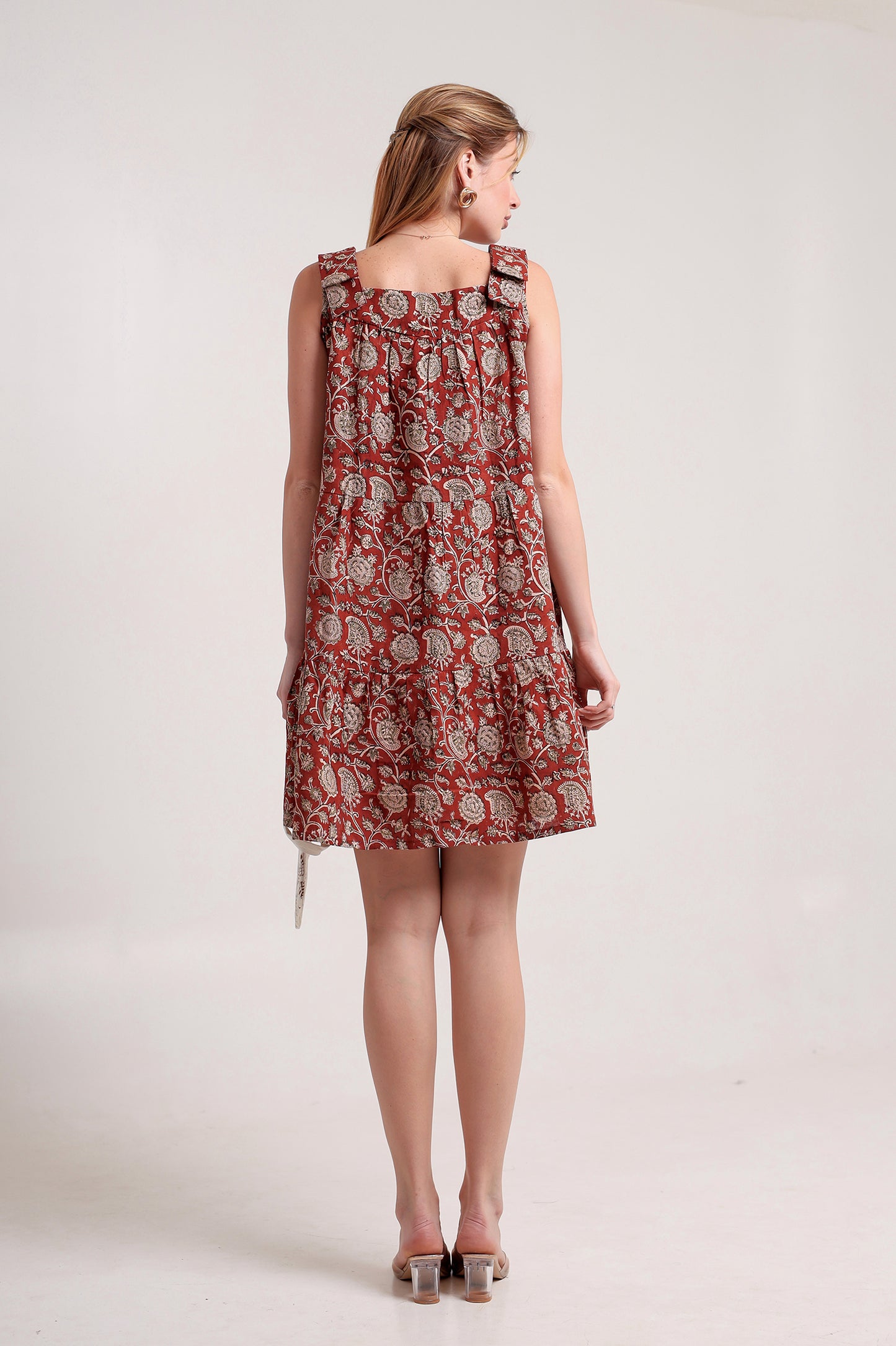 Woman wearing a red floral linen floral mini dress against a white background.