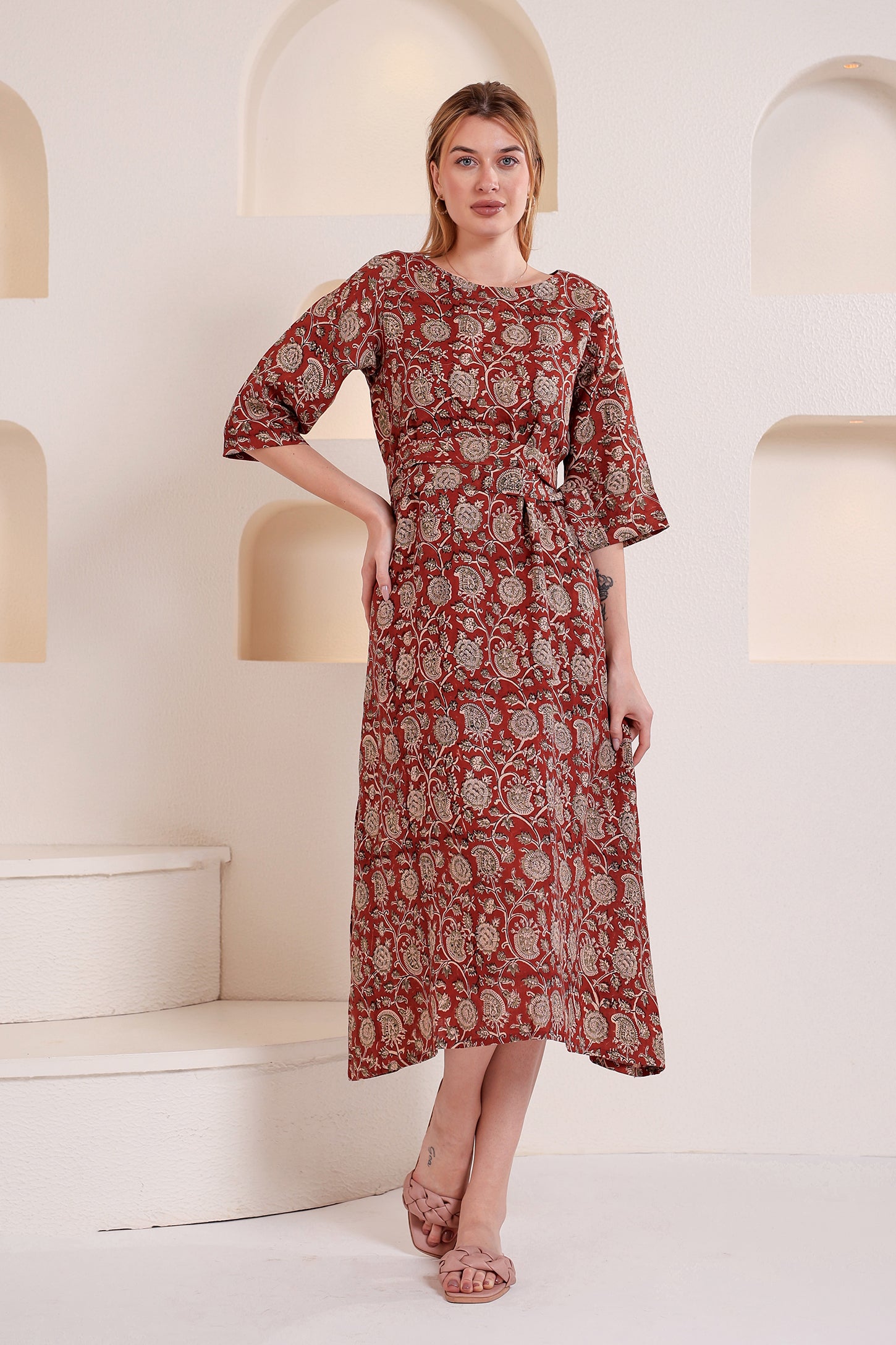 Woman wearing a red patterned linen floral maxi dress in a bright interior setting.