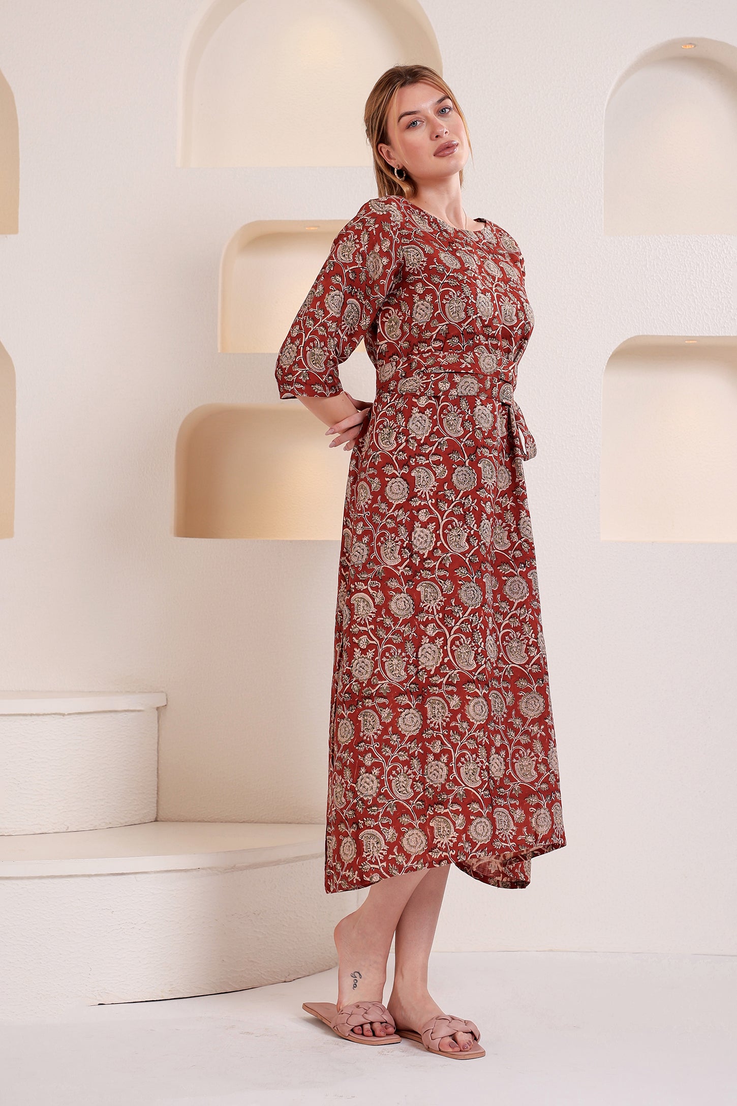 Woman wearing a red patterned linen floral maxi dress standing in a modern interior setting.