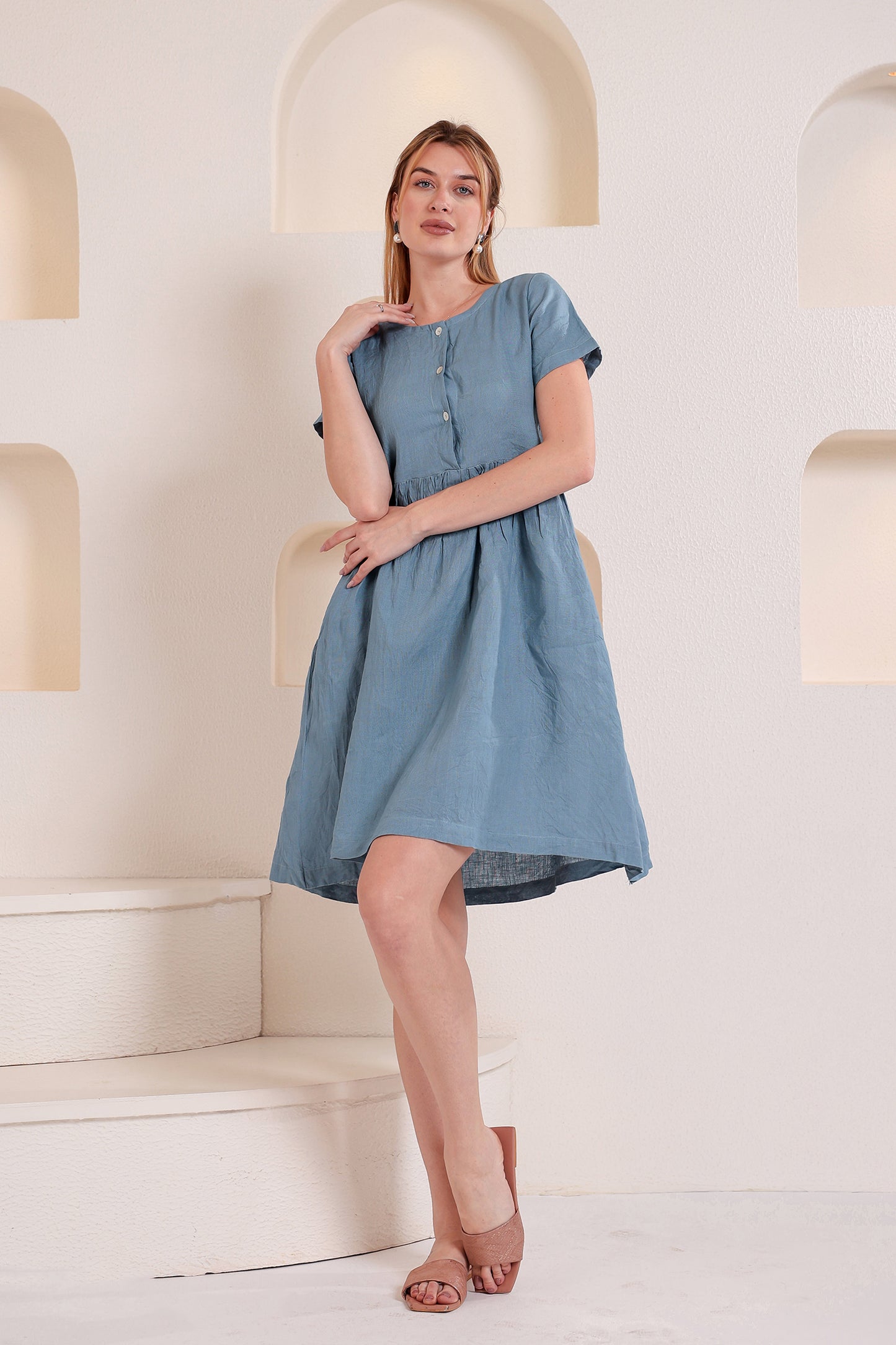 Woman wearing a blue linen midi dress in a softly lit indoor setting.
