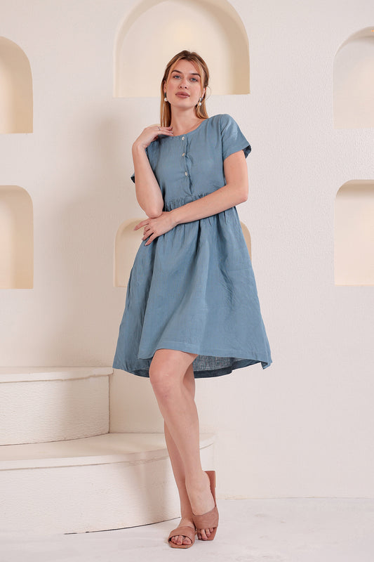 Woman wearing a blue linen midi dress in a softly lit indoor setting.