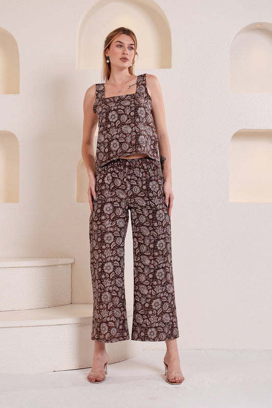 Woman wearing a patterned linen top and pants set standing in a minimalistic setting with arches.