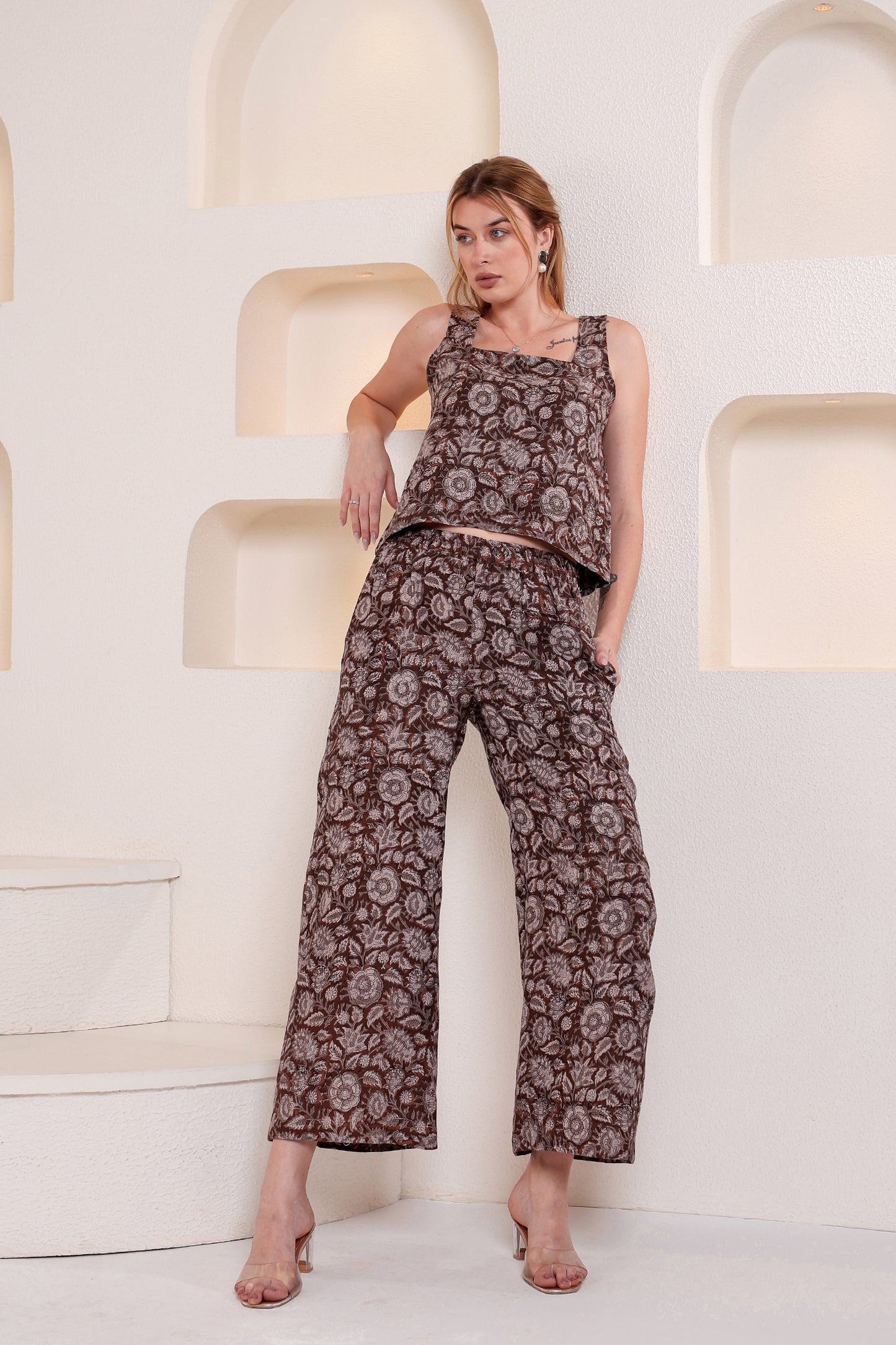Woman wearing a patterned linen top and pants set in a minimalistic setting.