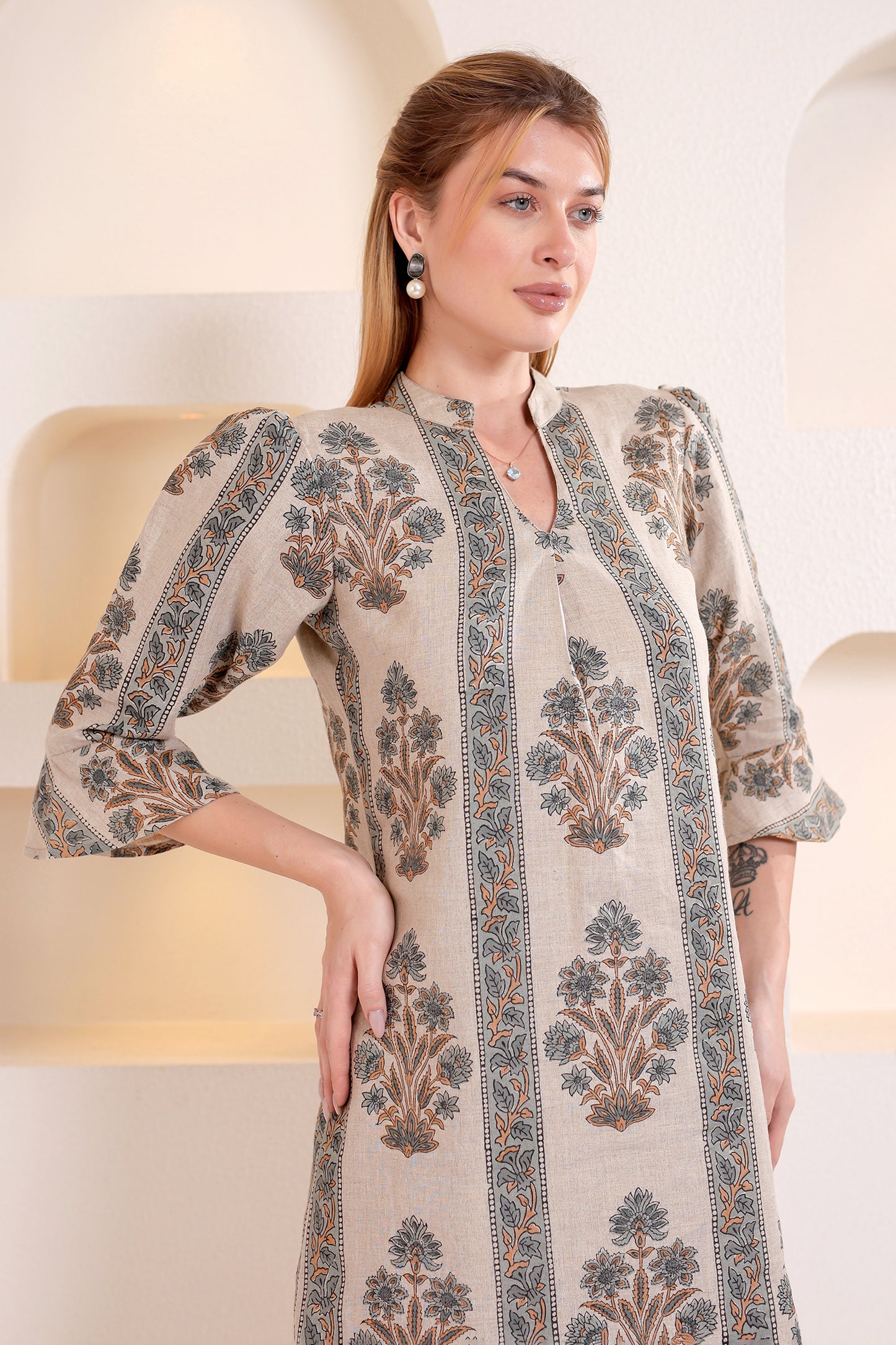Woman wearing a patterned linen midi dress against a neutral background.