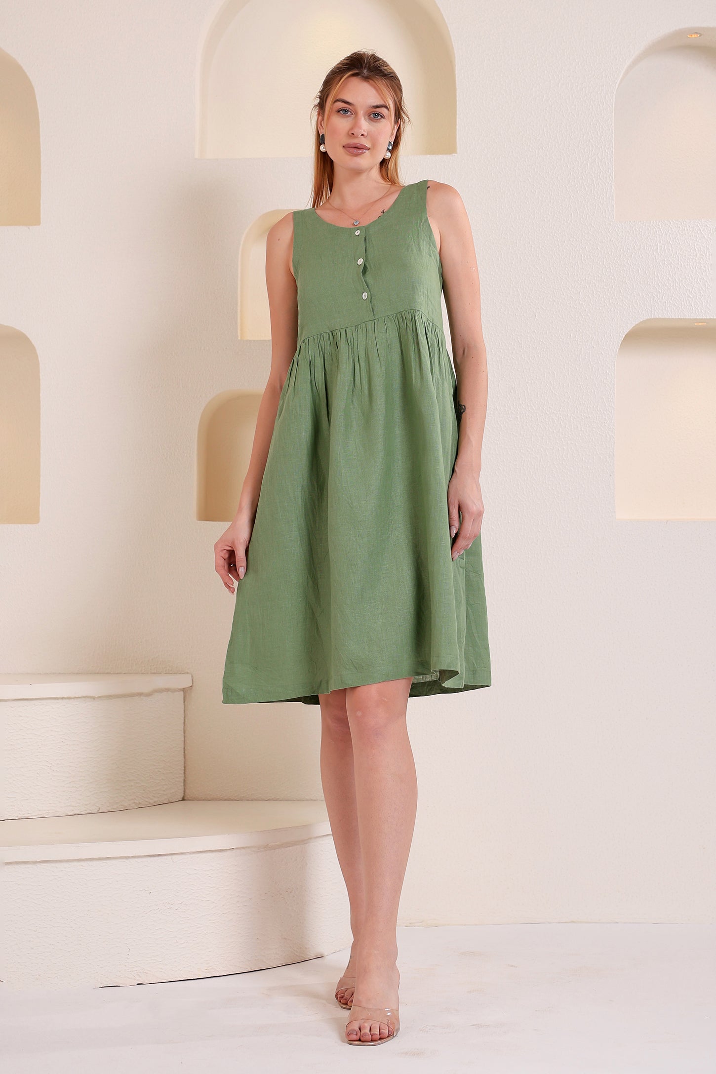 Woman wearing a green linen mini dress in a minimalistic setting.