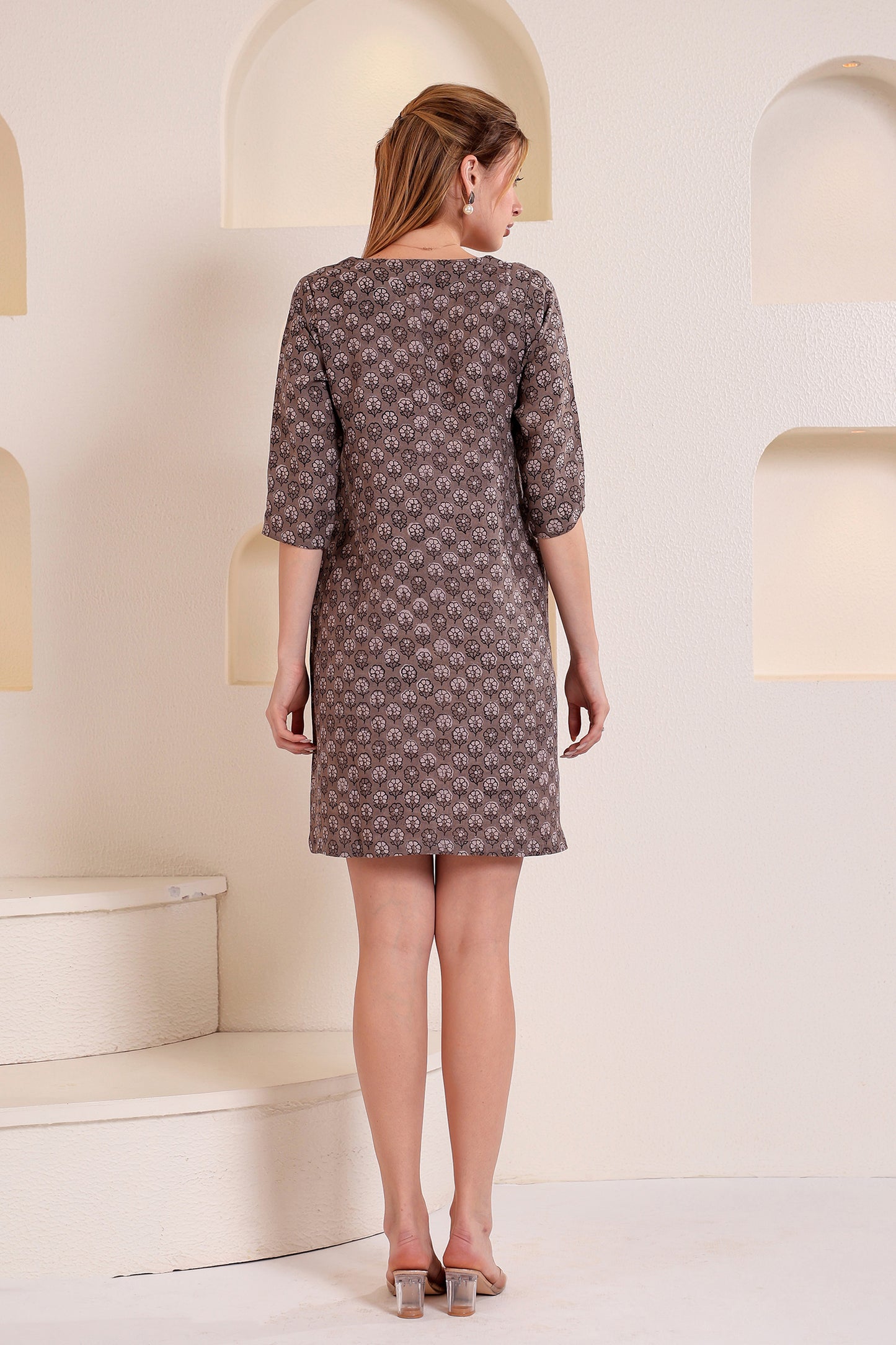 Woman wearing a patterned linen mini dress in a minimalistic setting.
