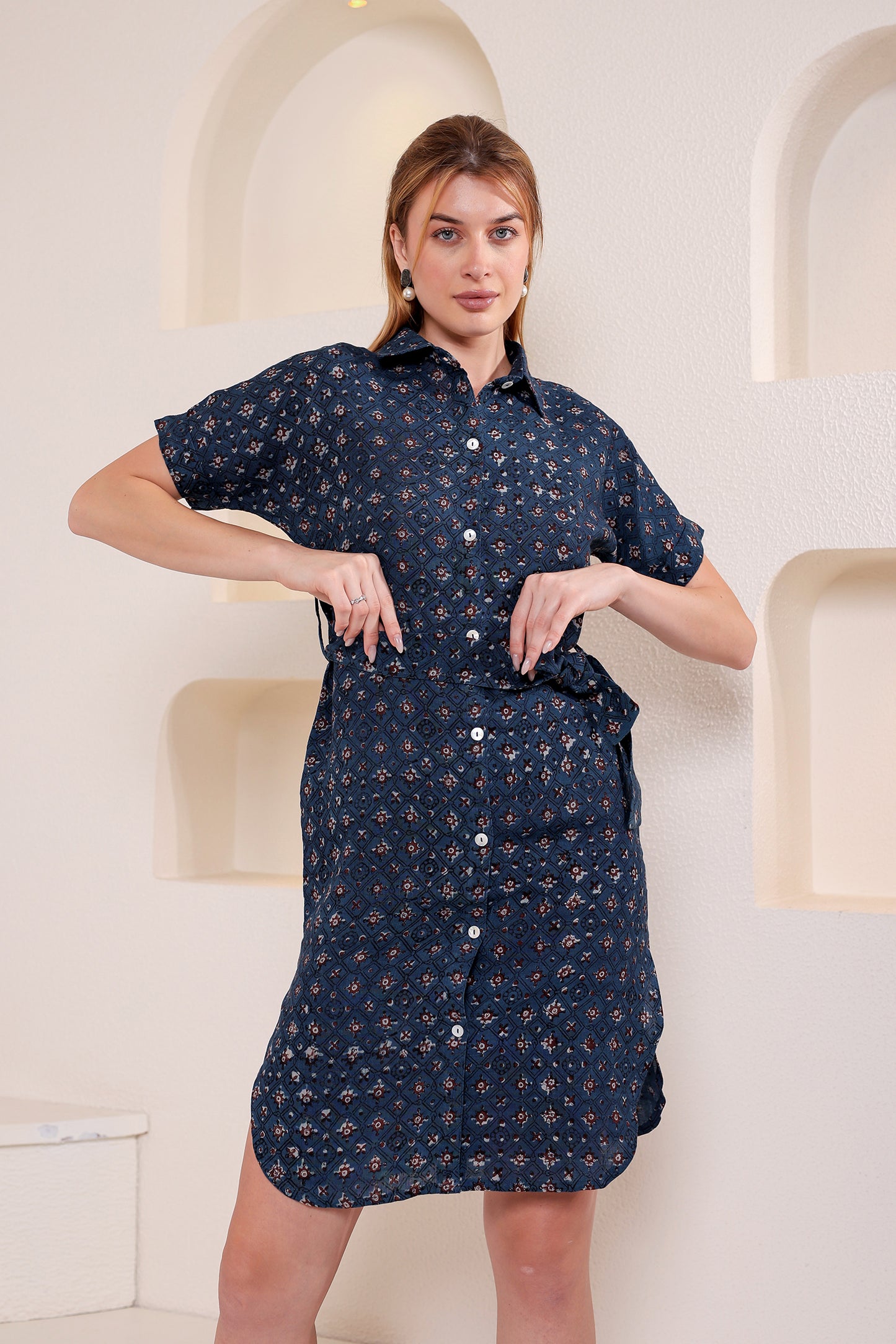 Woman wearing a navy blue patterned linen floral wrap dress against a white background.