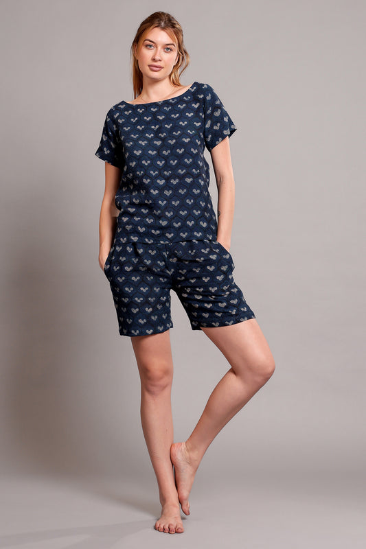 Woman wearing a navy blue patterned linen top and shorts pajama set against a gray background.