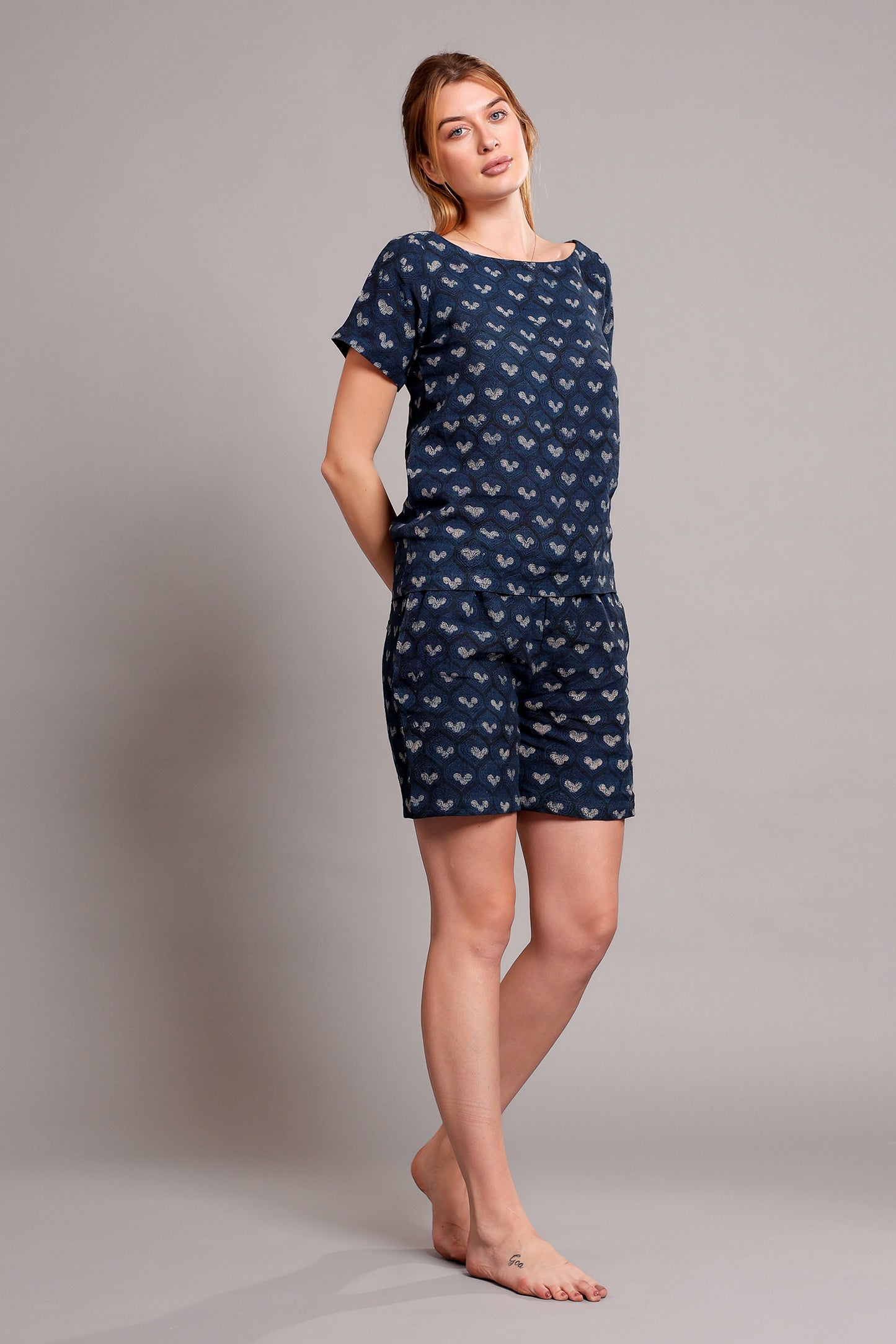 Woman wearing a navy blue patterned linen top and shorts romper against a gray background.