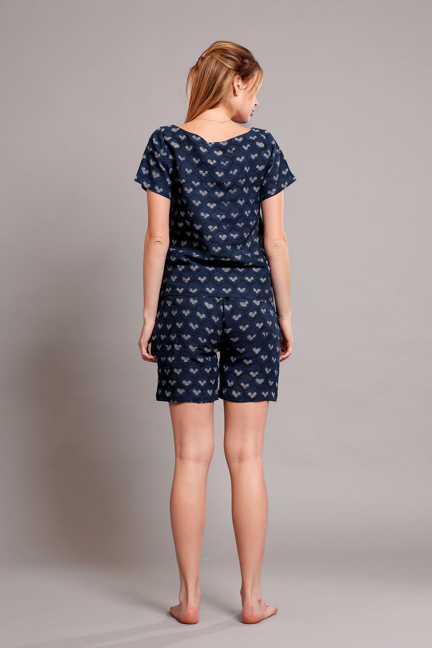 Woman wearing a navy blue patterned linen top and shorts set on a plain background.