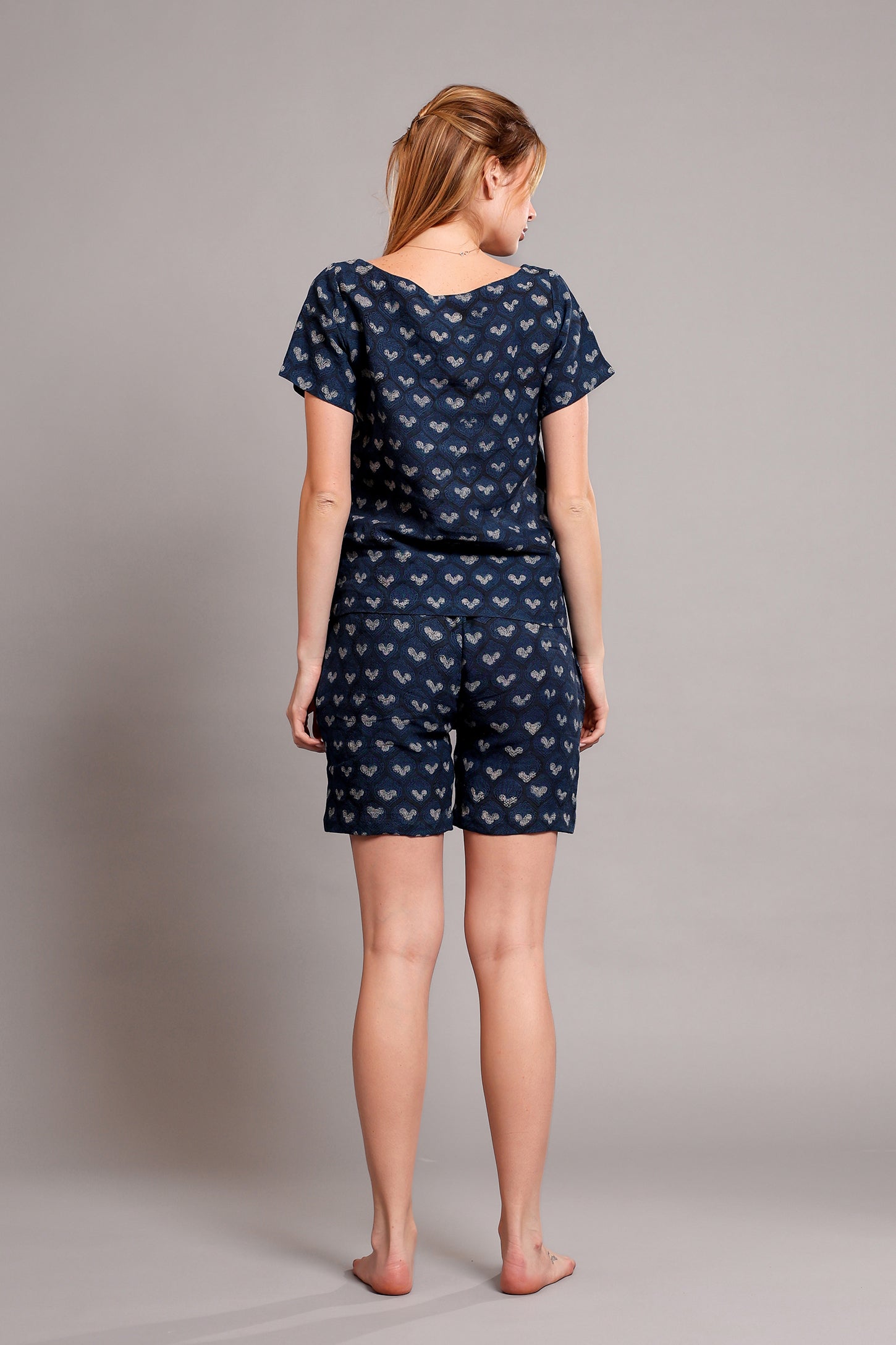 Woman wearing a navy blue patterned linen top and shorts set on a plain background.