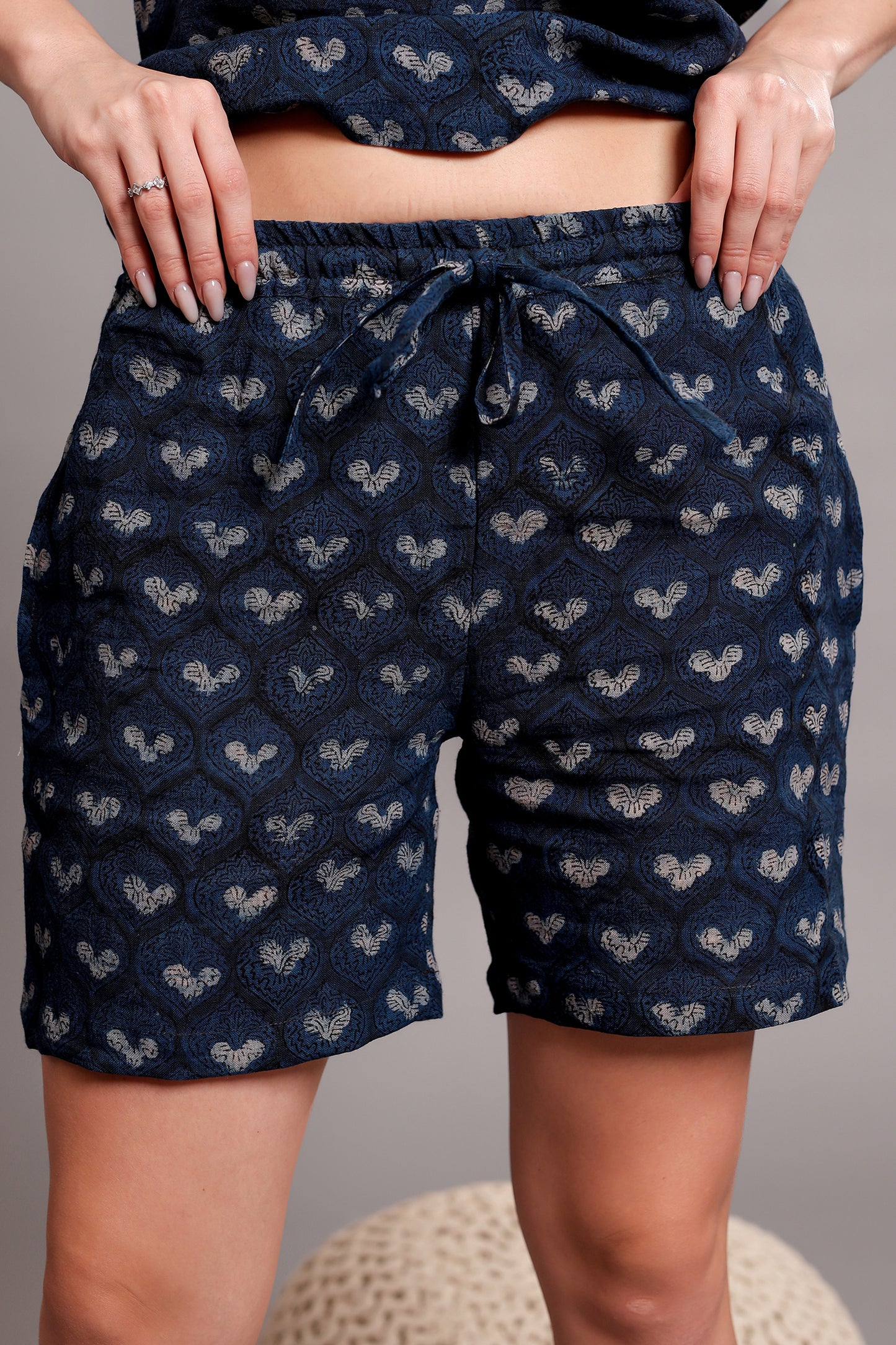 Person wearing navy blue linen shorts with a subtle pattern against a gray background.