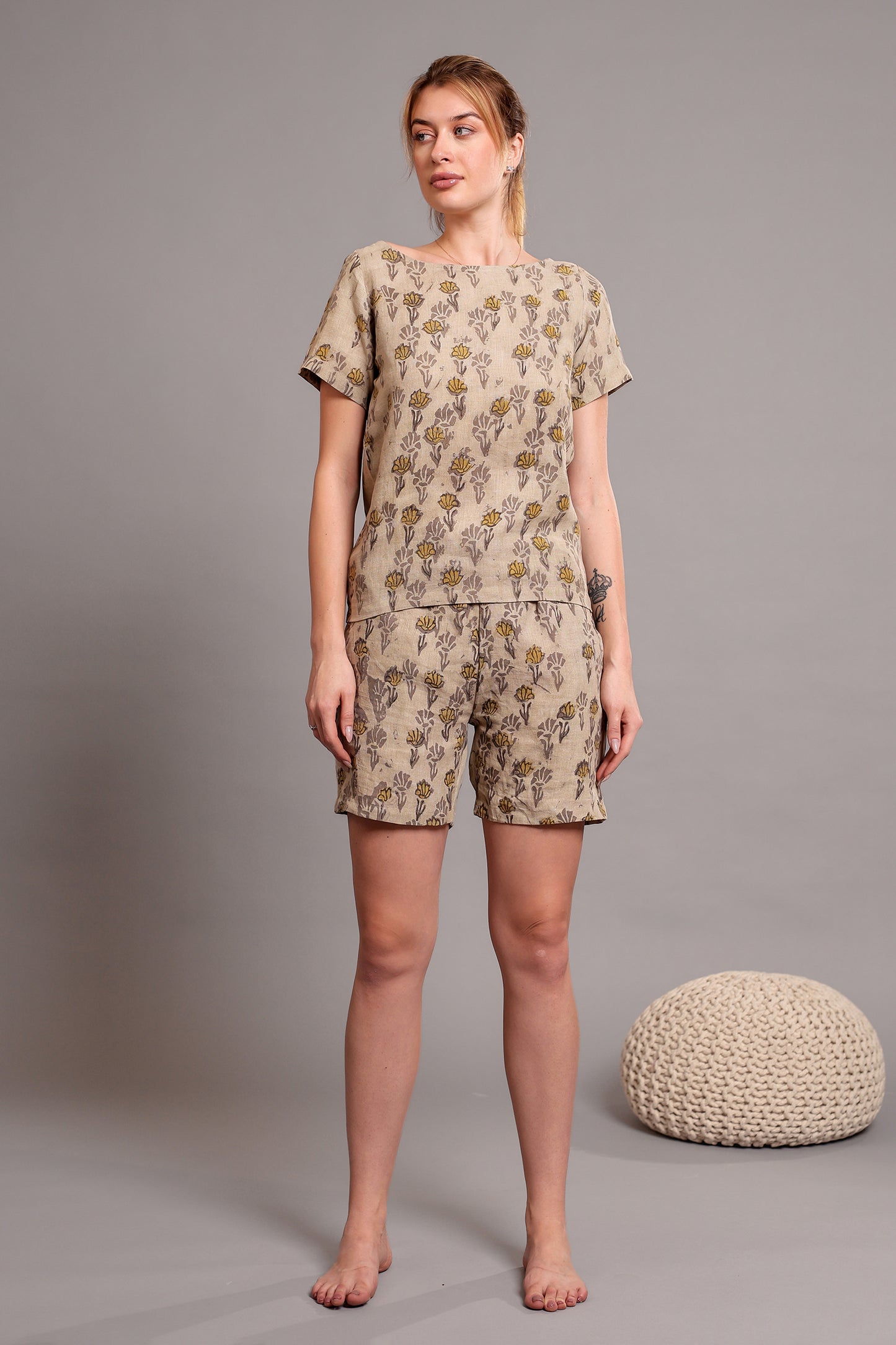 Woman wearing a matching linen floral top and shorts set against a beige background.