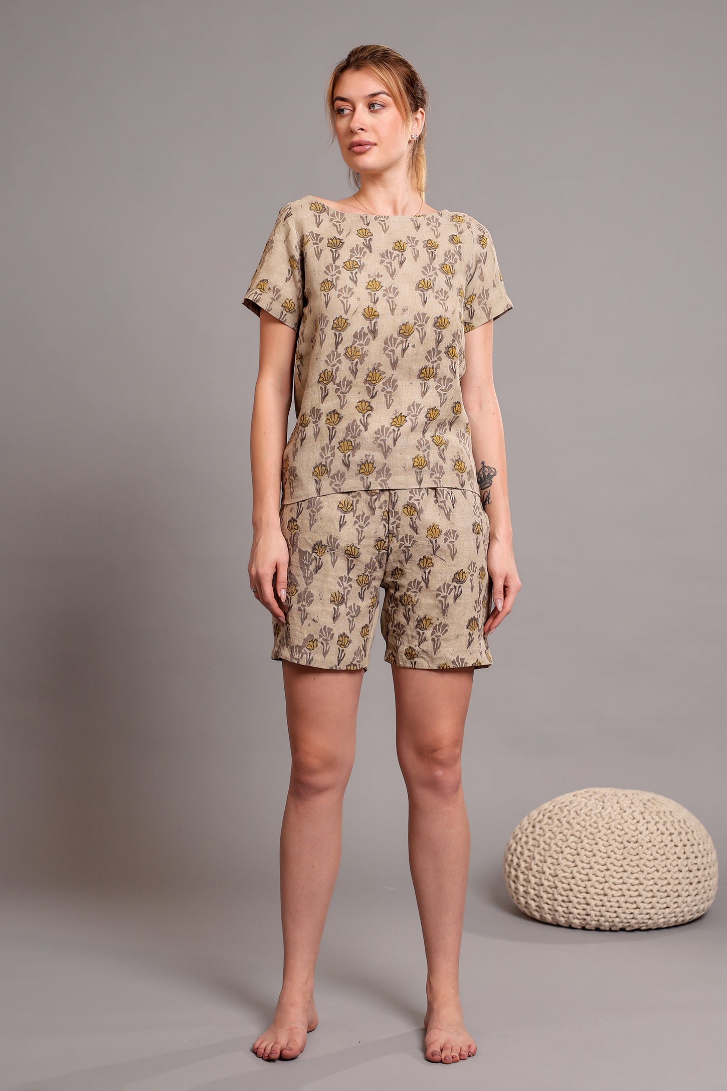 Woman wearing a matching linen floral top and shorts set against a beige background.