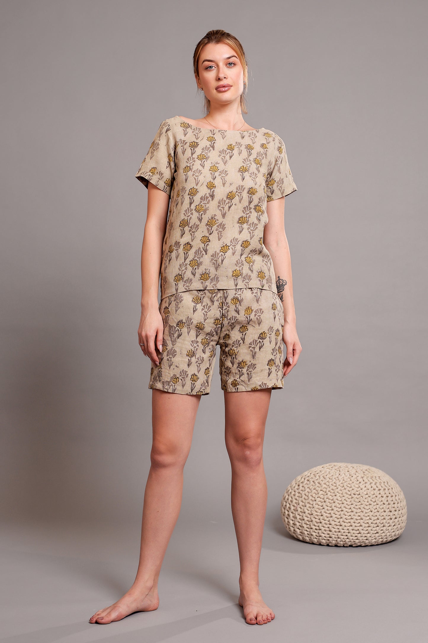 Woman wearing a linen floral top and shorts pajama set against a gray background.