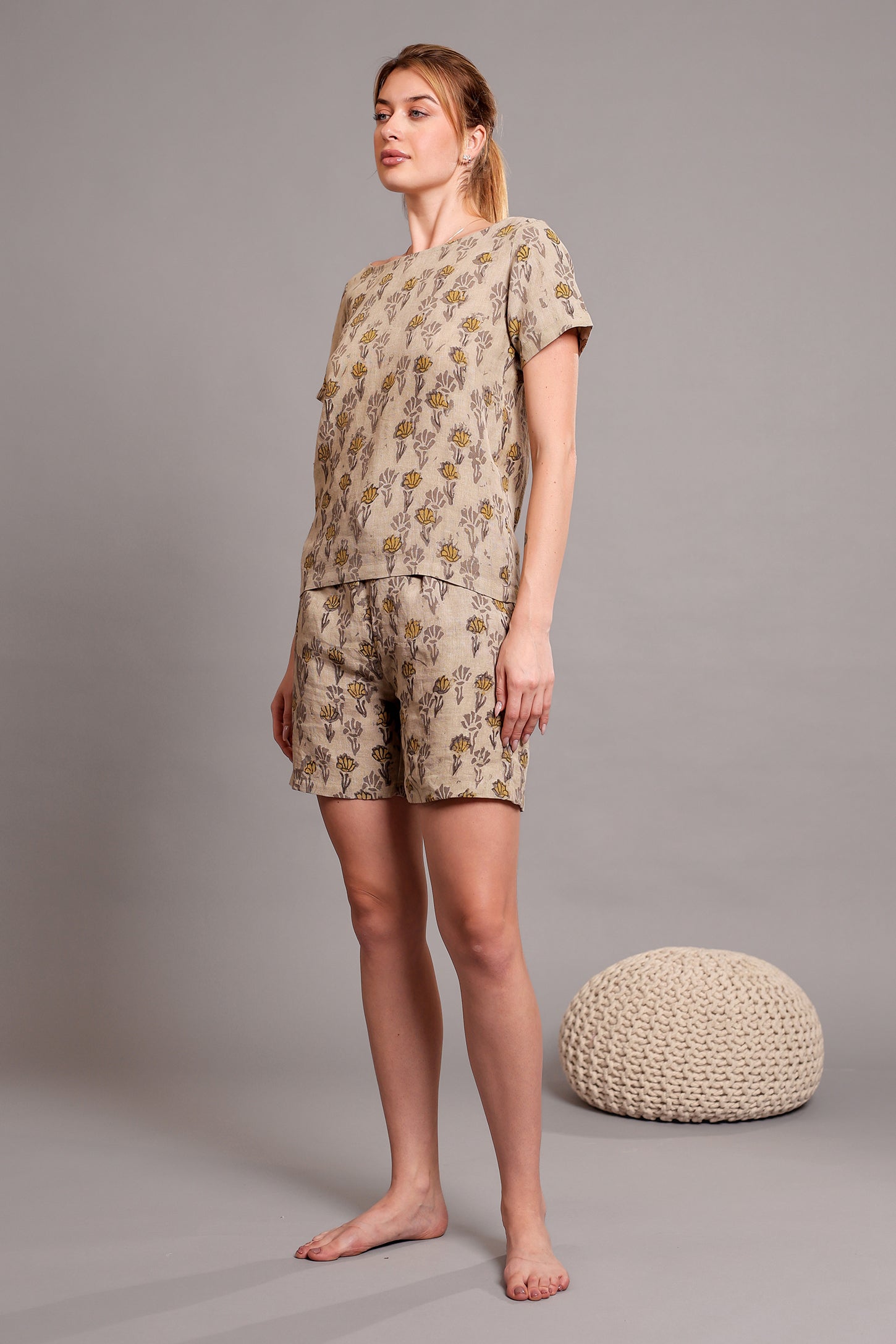 Woman wearing a linen floral top and shorts set against a gray background.
